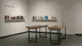 Two small vitrines stand in the center of the SVA Gramercy Gallery lobby. Behind them, two walls each have a single wooden shelf holding front-facing books of various sizes. A small sign above the shelves reads “Picture Library 2025.”
