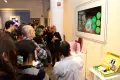 Guests at the opening reception of the annual spring gallery show admire a screen of rotating student advertising work.
