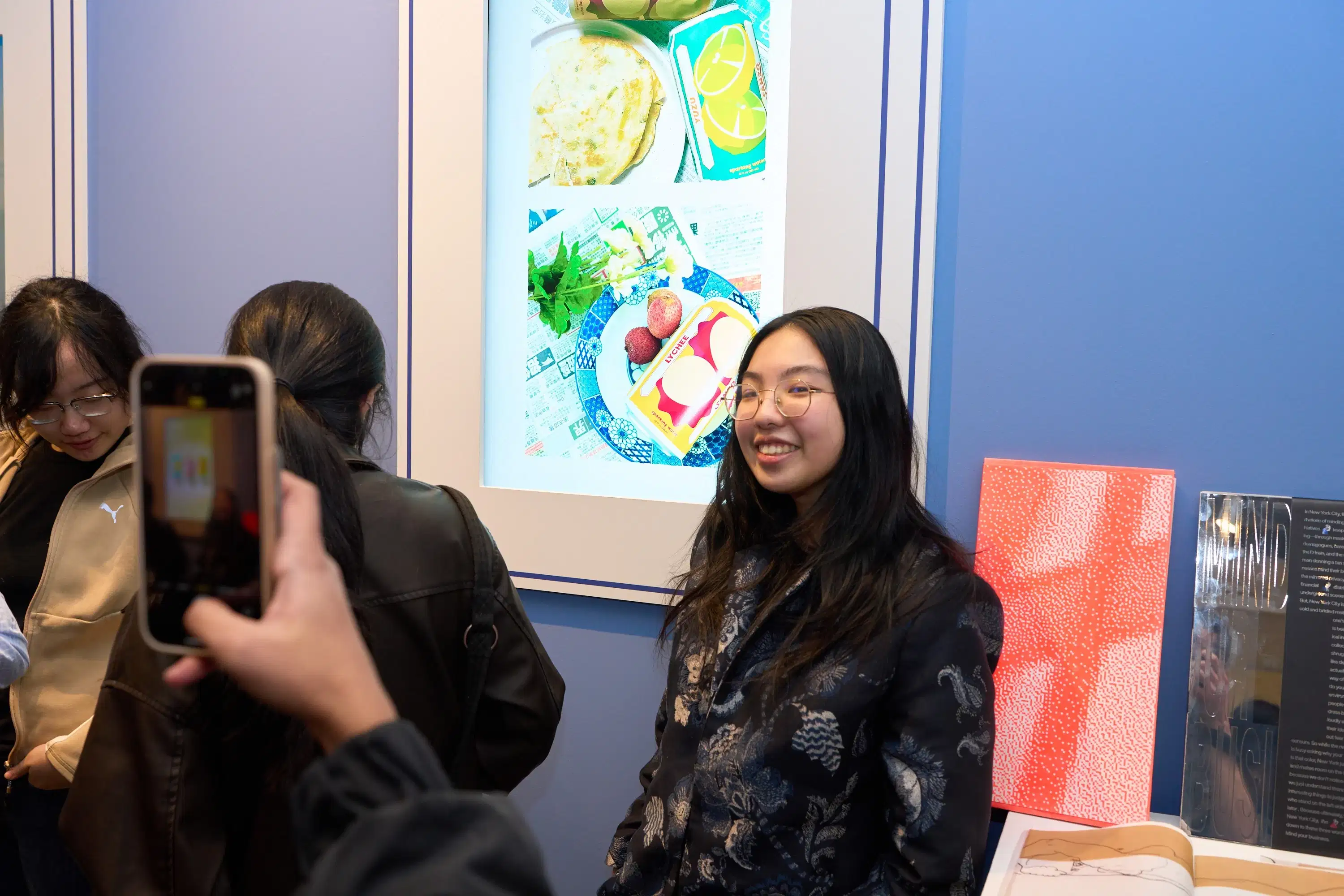 A student smiles for a photo as her work plays on a screen at the annual spring gallery exhibition.