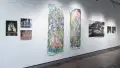 A row of several artworks hangs on the wall, ranging in size and color.