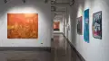 The right hallway of the gallery, with paintings hung on walls in the foreground, and all the way in the background.