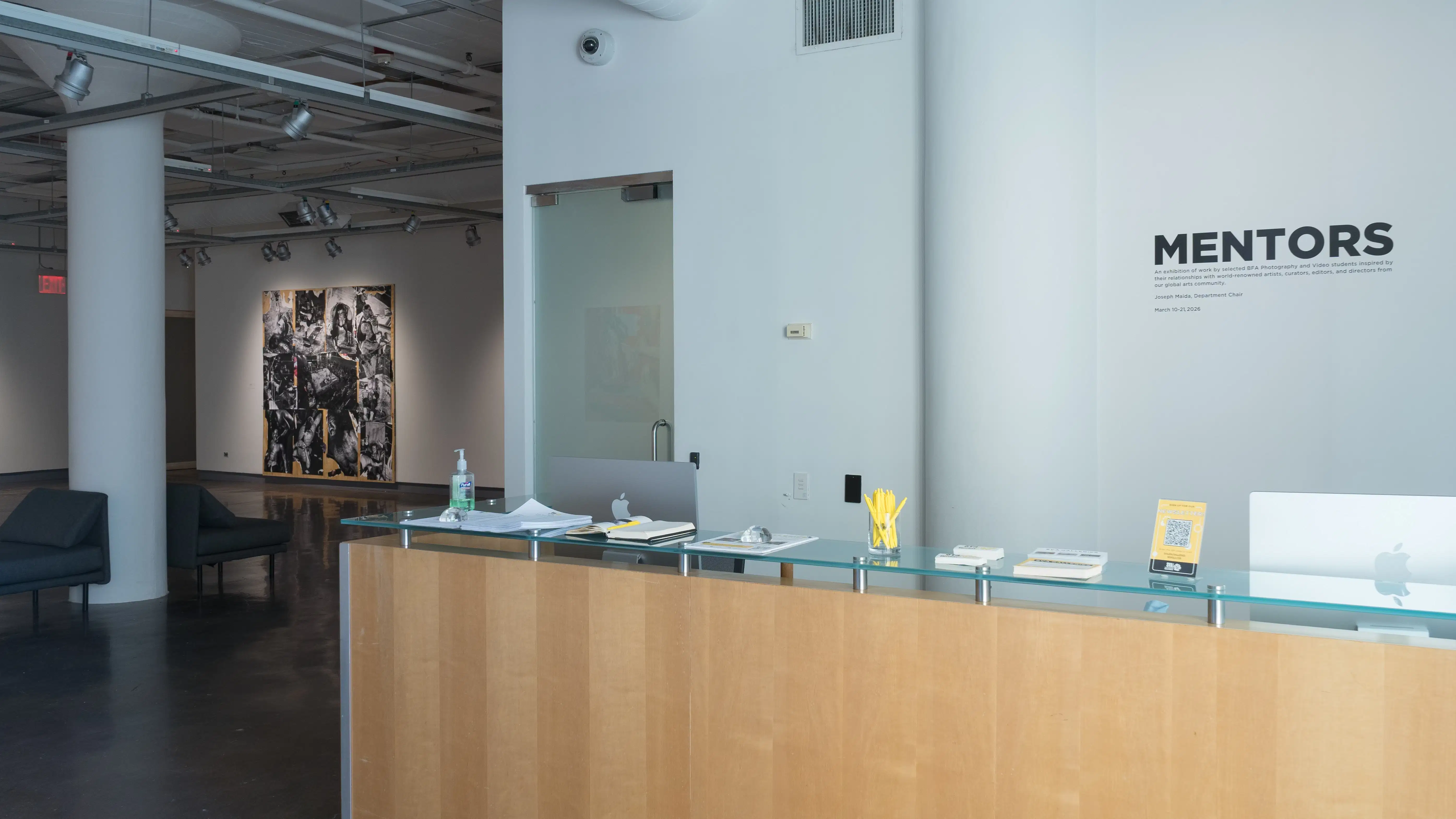 Upon entering the SVA Chelsea Gallery, wall vinyl above the front desk reads “MENTORS.” Beyond the desk, artwork is visible in the first gallery.