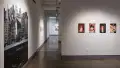 A large vinyl photograph of overlapping buildings takes up much of the wall in the gallery’s hallway. A row of four photographs featuring a model is pinned to the wall perpendicular to it.