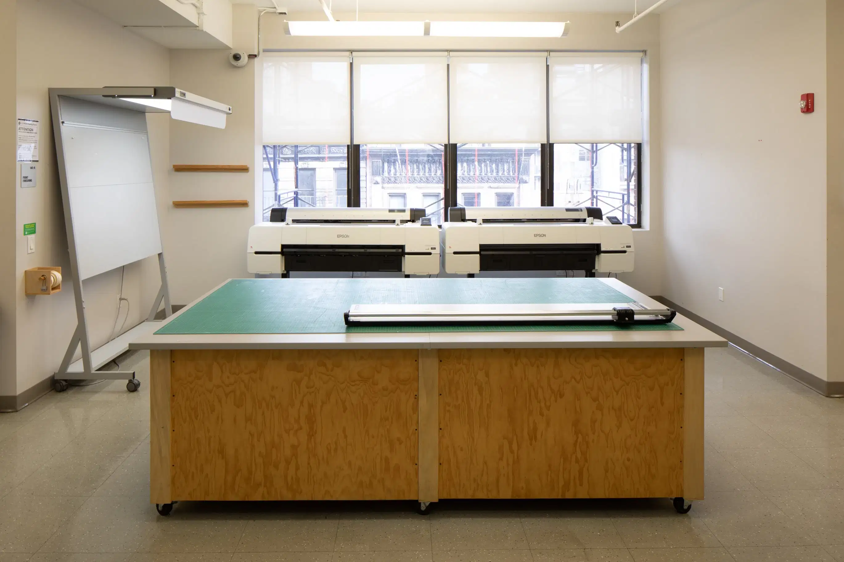A large cutting table, with large digital printers in a lab.