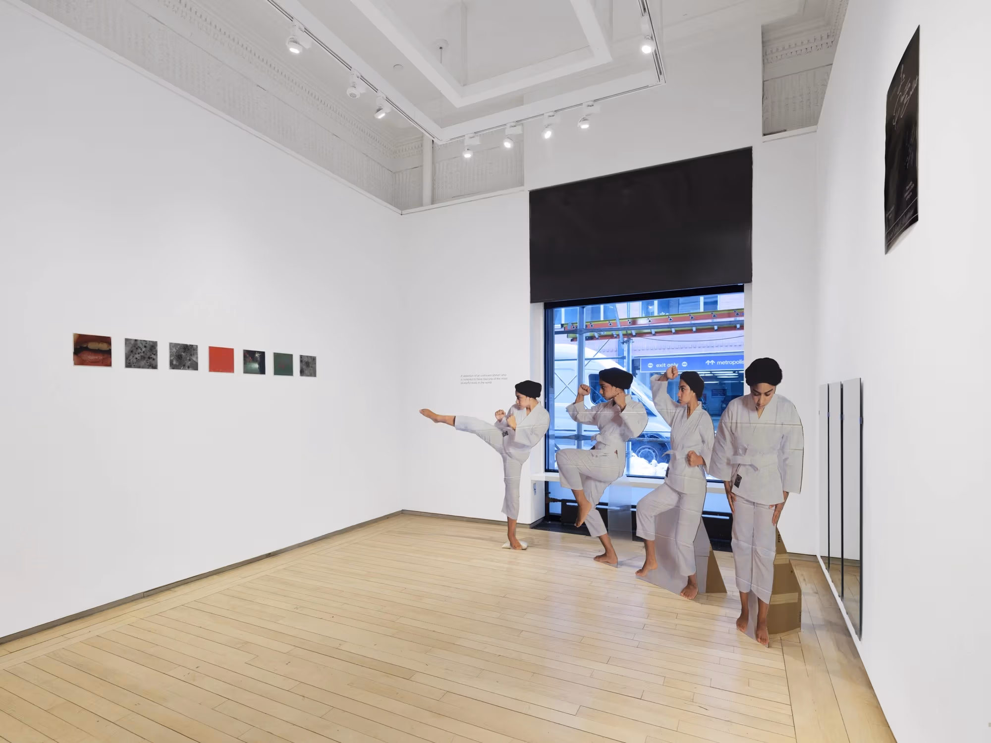 A corner of the SVA Flatiron Project Space, with prints on the left wall, and cardboard cutouts on the right.