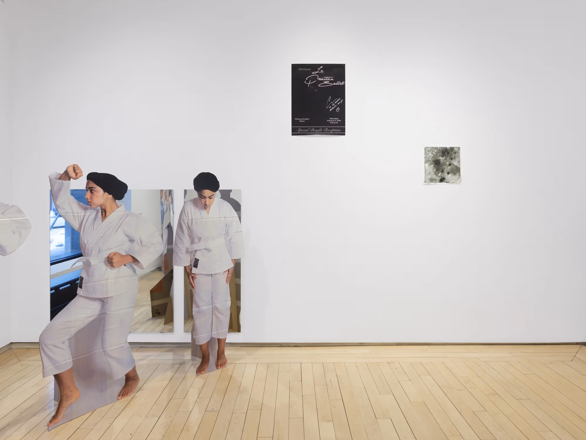 Multiple items decorate the gallery wall, including reflective materials and prints, with cardboard cutouts in front of it.