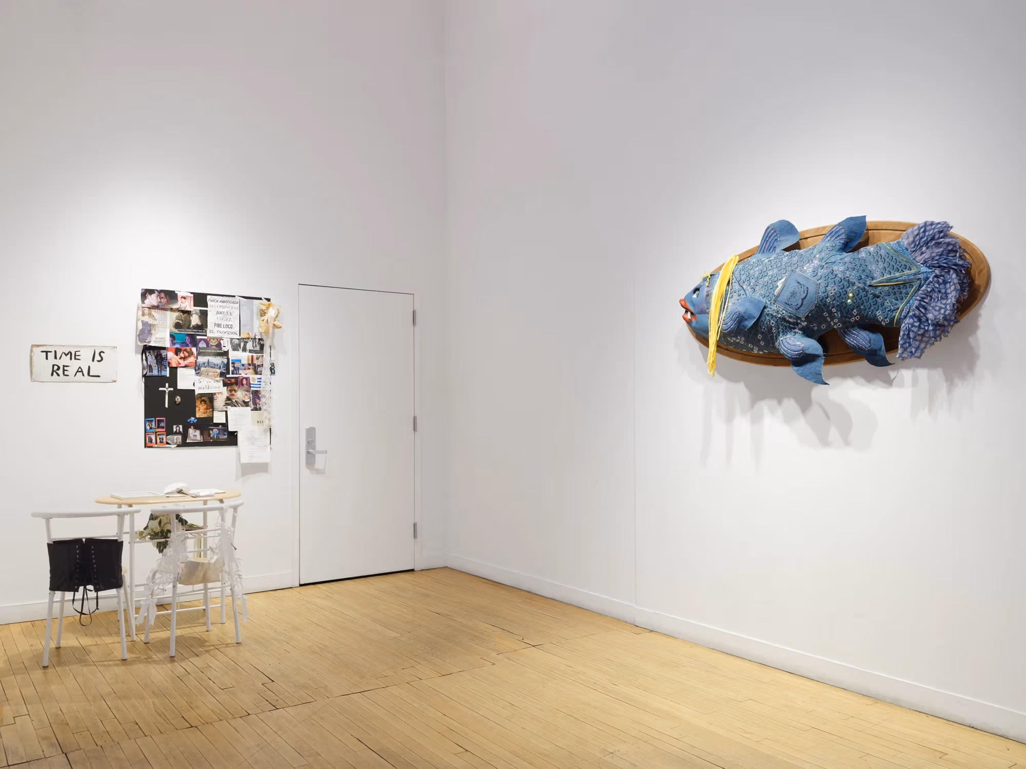 A corner of the gallery with mixed media artwork on both sides.