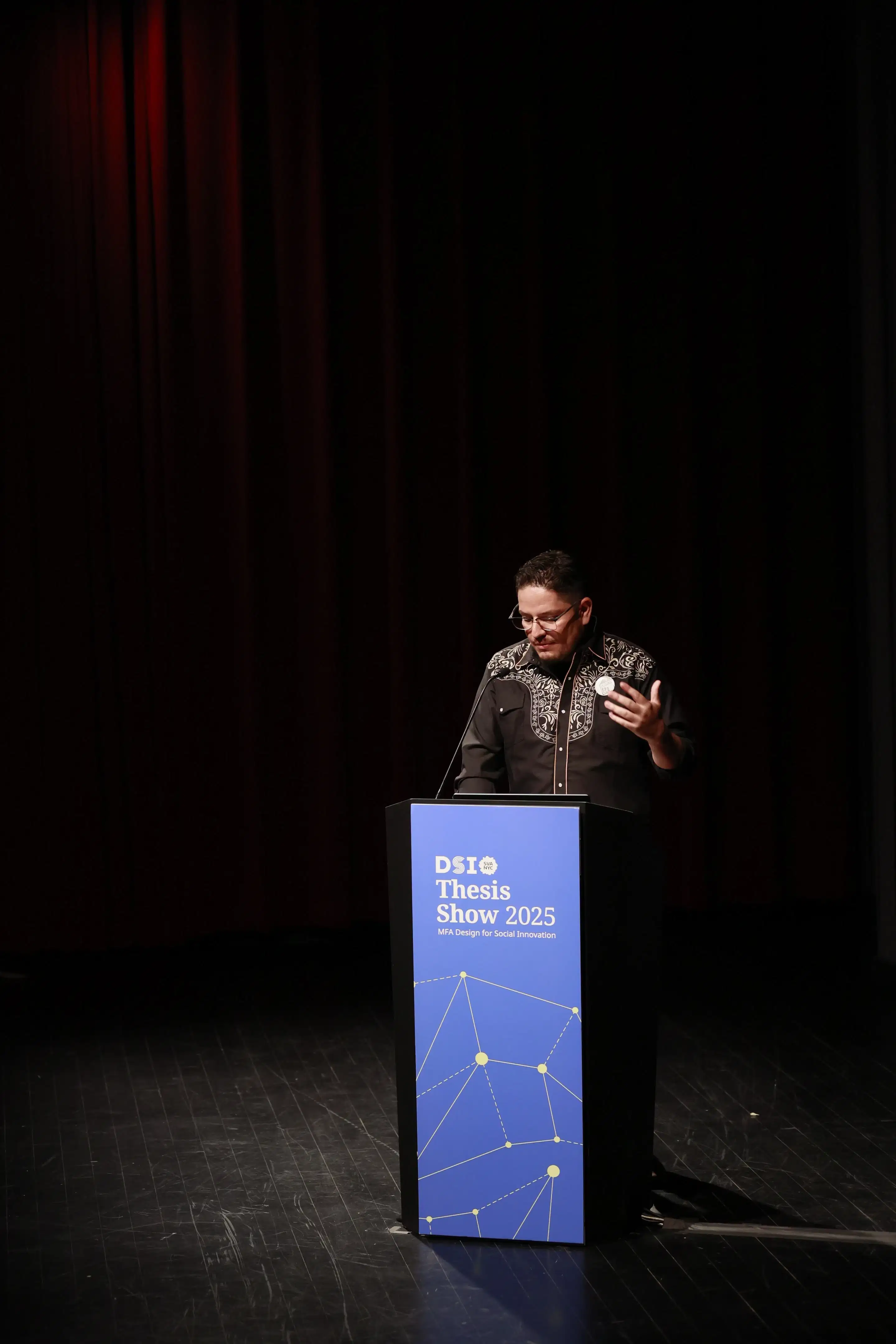 Person speaking at podium with text reading DSI Thesis Show 2025