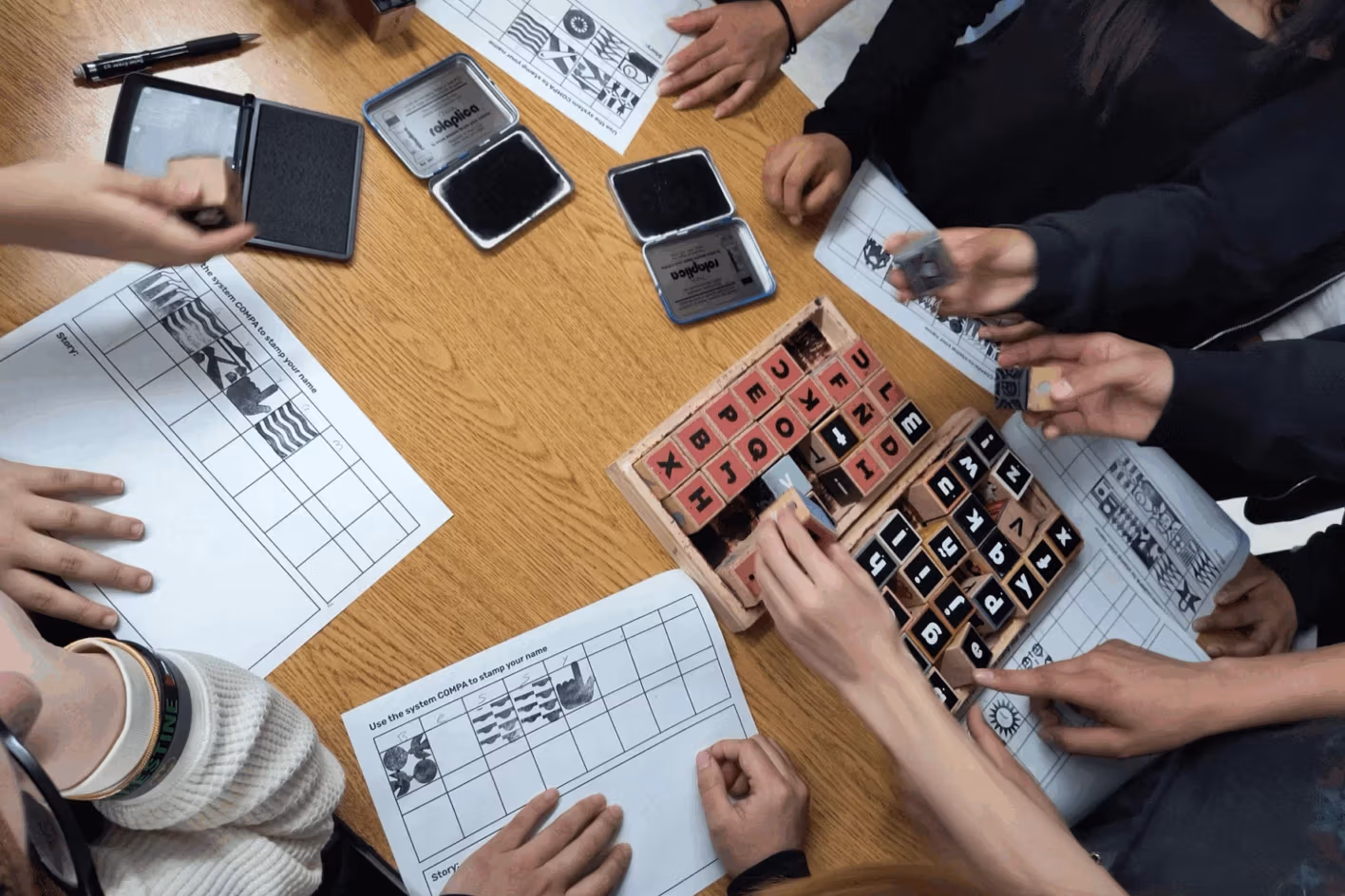 Hands touching papers and stamps on a table