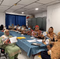 Group of people sitting around table holding cookbooks