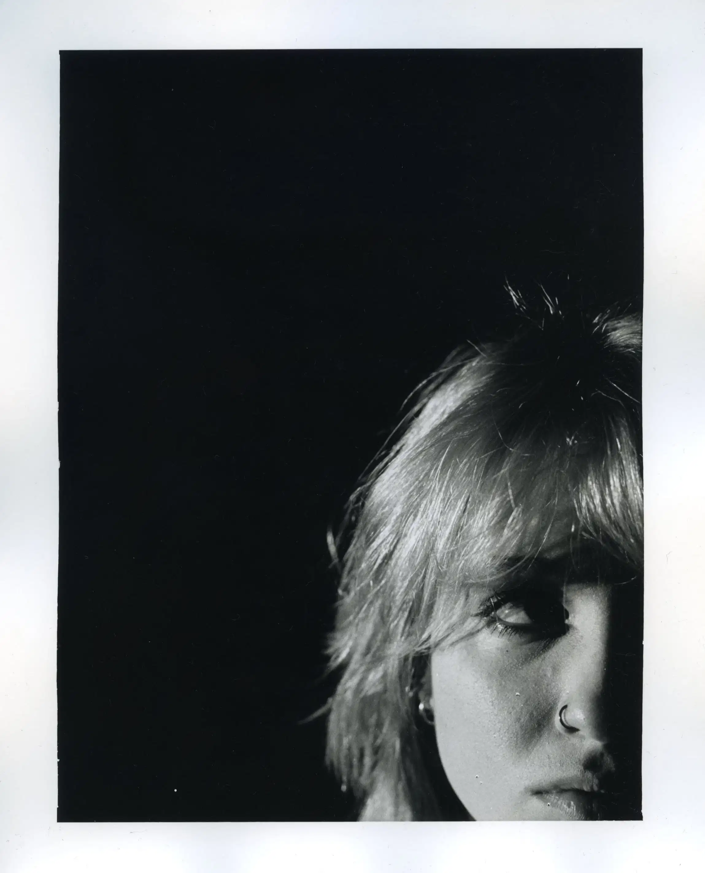 Picture of a blonde girl in the lower right corner, looking away, with black background