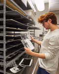 A student looks at prints in front of a drying rack