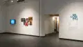 An angled view of the front gallery at Gramercy gallery, showing the title wall vinyl reading “Becoming” on the right of a doorway; a large print with multiple images and a monitor reading “perception” on the left.