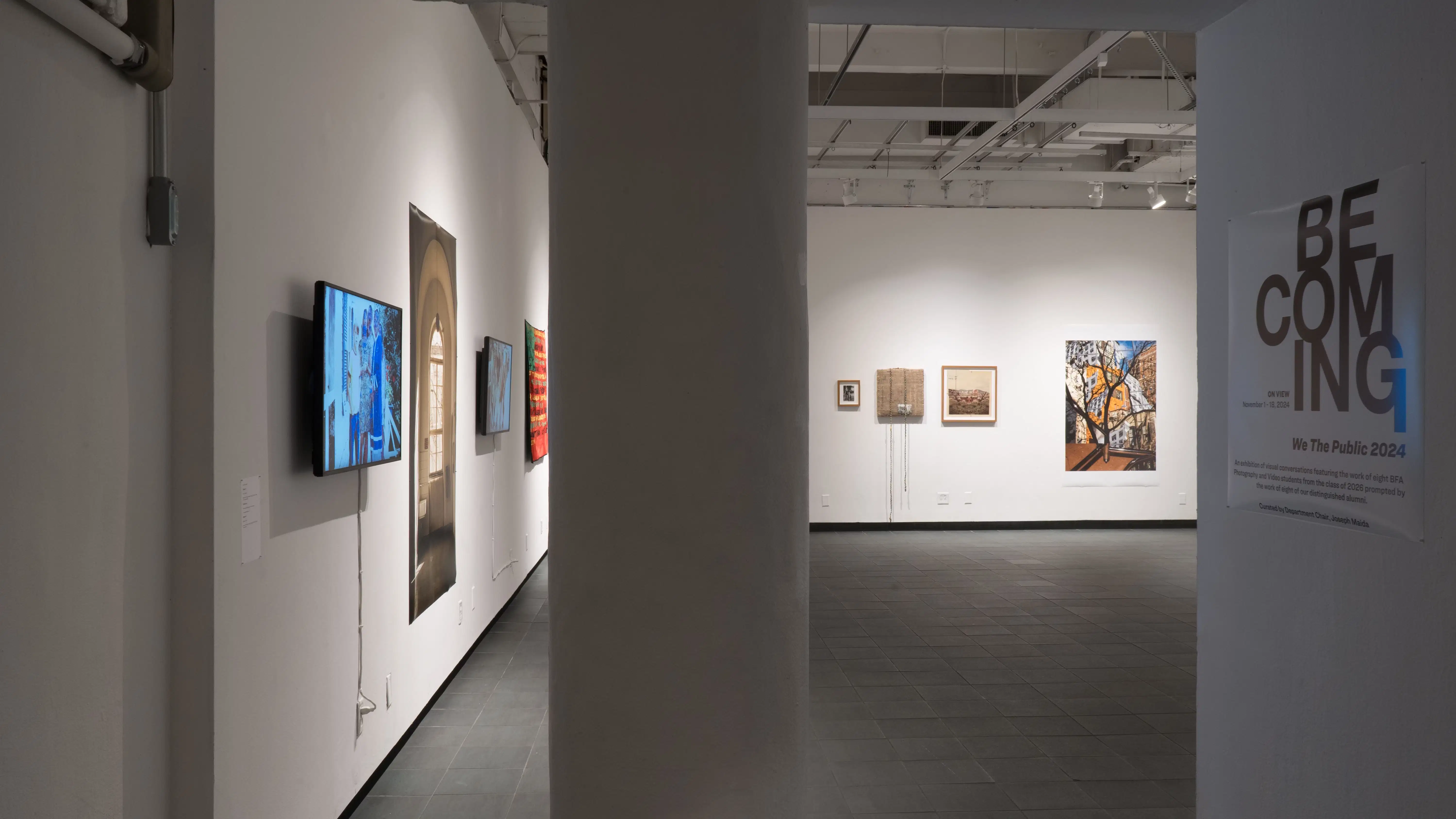 A view through the doorway into the back gallery at Gramercy Gallery, with a column in the  middle foreground, a monitor directly inside on the left, and many large prints and framed works inside.