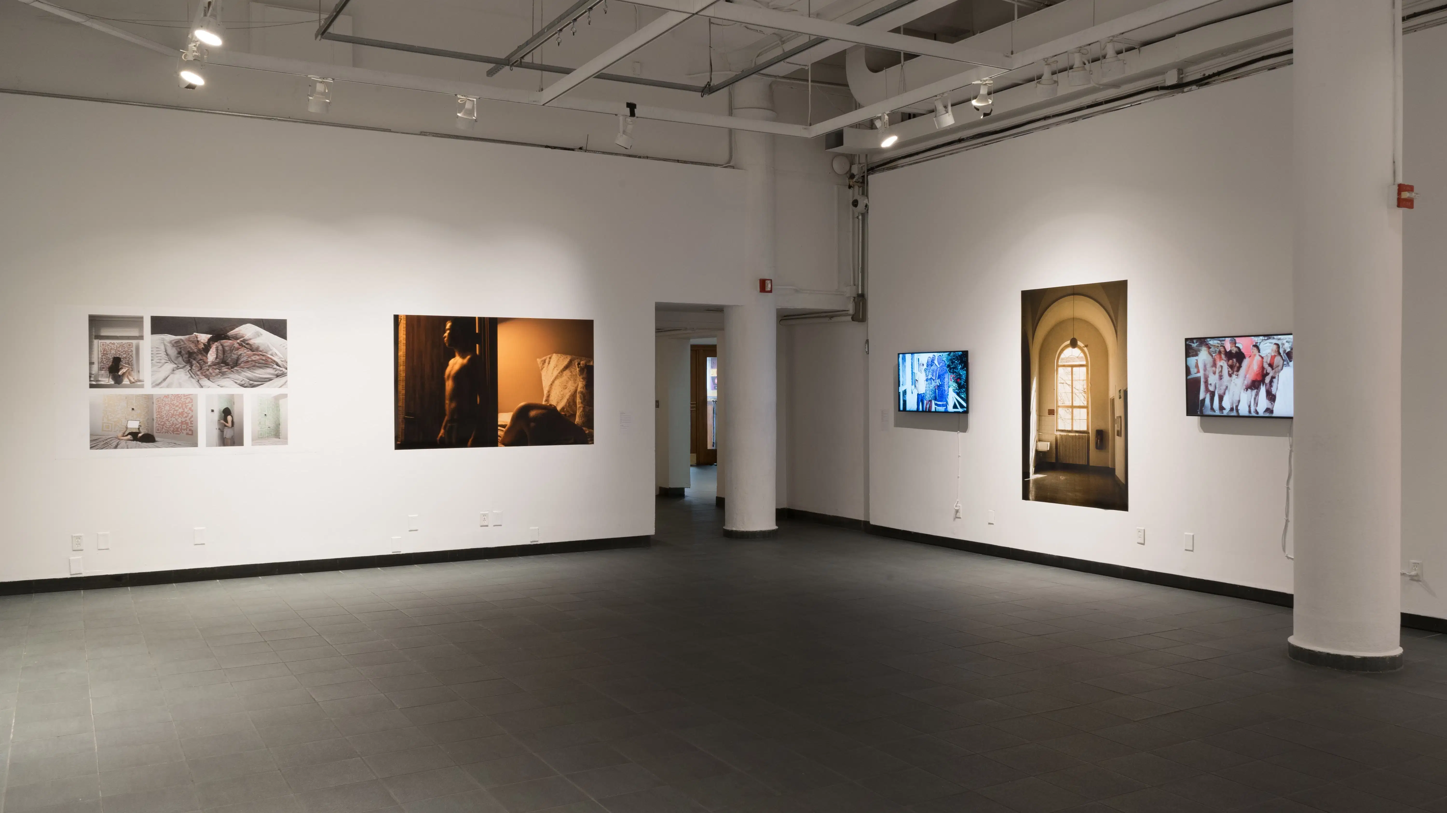 An angled view of the back gallery at Gramercy gallery, showing multiple large prints and monitors on the walls.