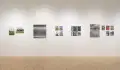 Straight shot of one wall in the Flatiron Gallery, showing multiple prints of industrial moments in varying sizes lining the walls, and an extra large print in grey on the right.