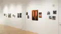 Angled shot of one wall in the Flatiron Gallery, showing multiple prints of industrial moments in varying sizes lining the walls, and an extra large print in orange showing two arches in the foreground..