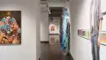 Looking down the right hallway of the SVA Chelsea Gallery, some works from gallery one are still visible. A painting of a woman’s face hangs on the very back wall of gallery four. A mixed-media textile installation hangs on the right side of gallery two.