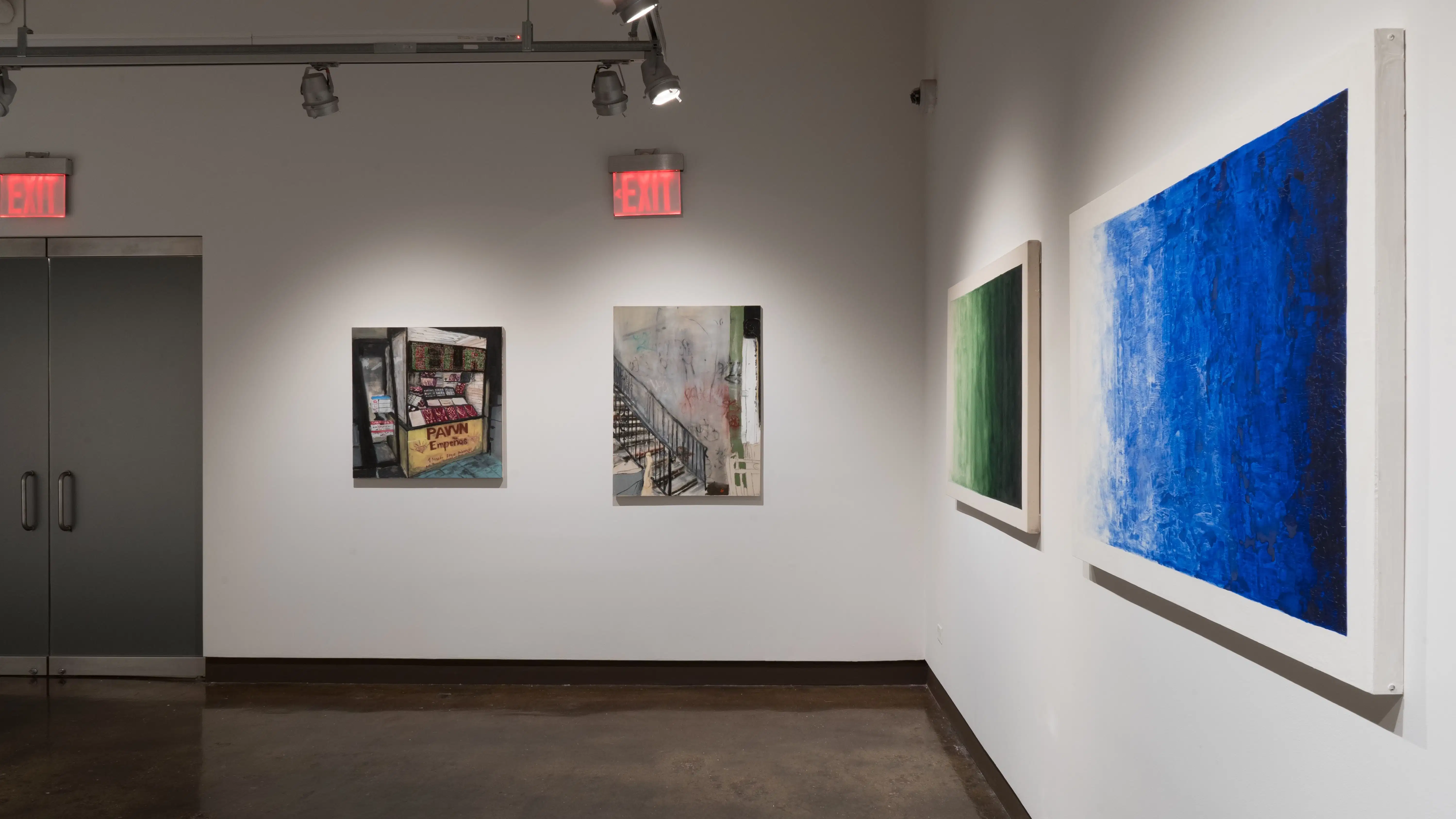 In the opposite corner,  two greyish paintings depicting scenes of city life hang beside two large swatches of color.