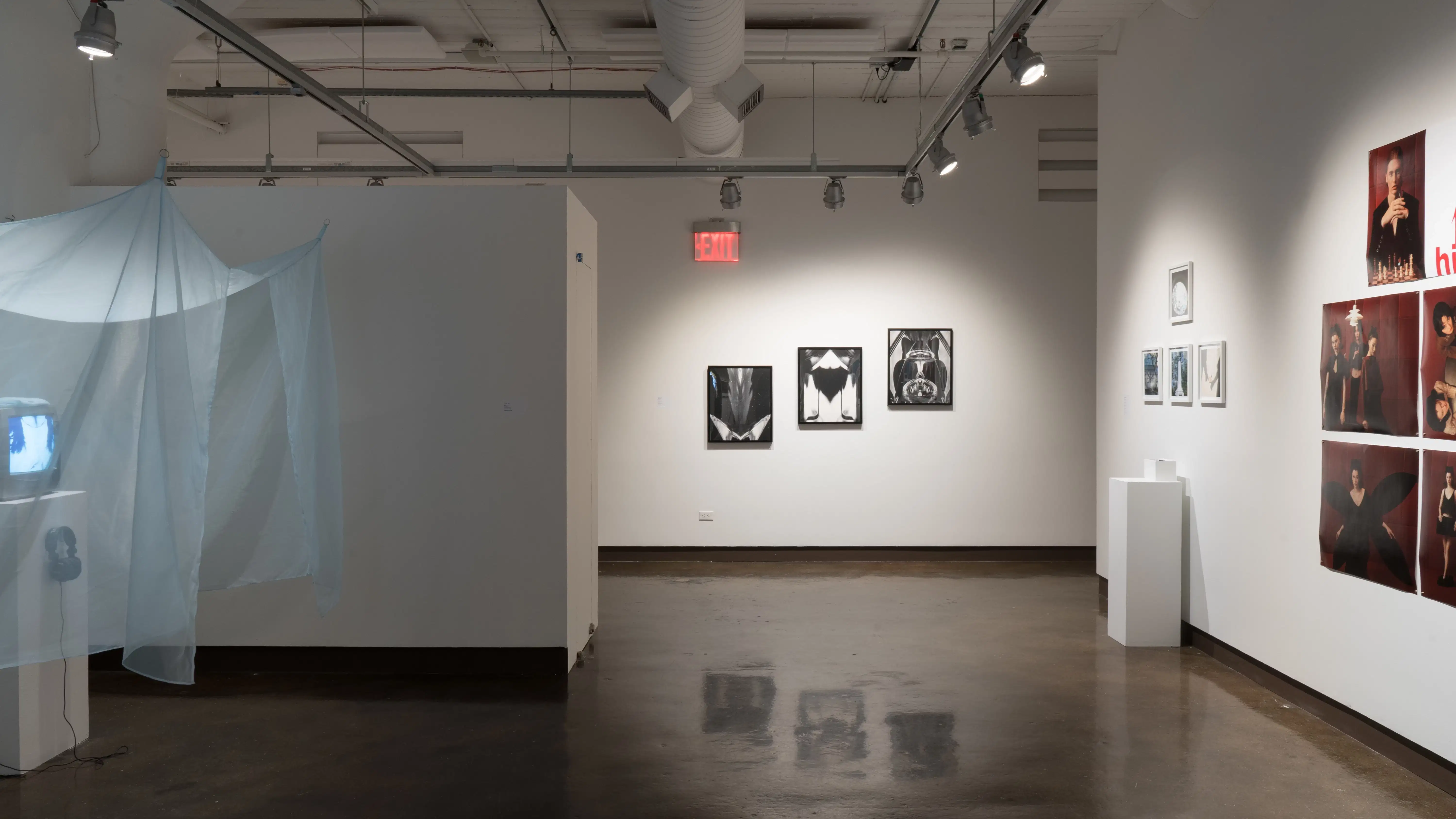 General view of gallery 3 space looking down to the hallway where three mirrored grayscale photographs are hung in an inclination. 