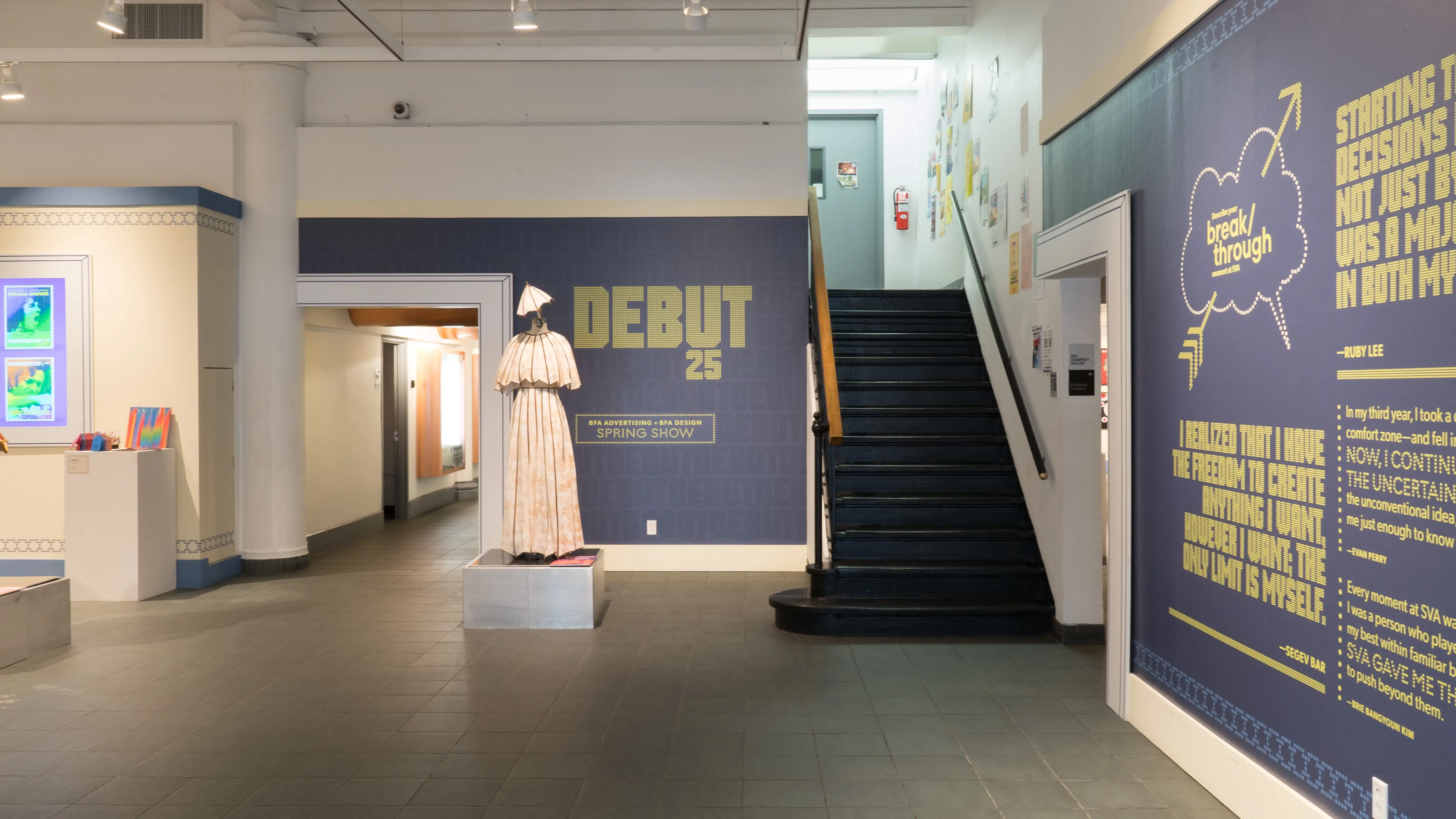 Upon entering the SVA Gramercy Gallery lobby, quotes and information about the exhibition are presented in vinyl text on the right wall. Straight ahead, a mannequin is dressed in a umbrella-inspired outfit. 
