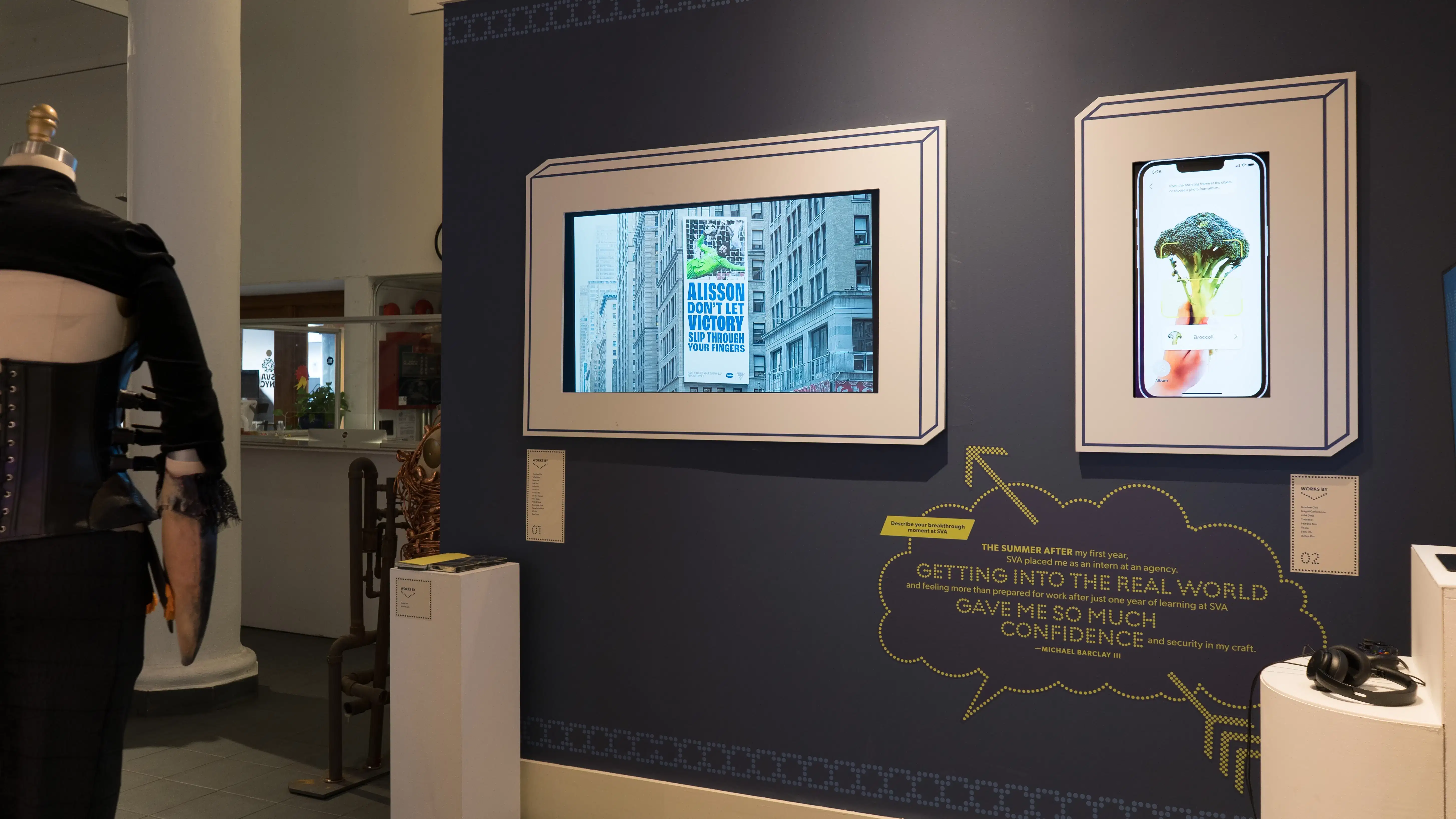 On one of the walls in the lobby area, one monitor displays a large billboard design, while the next monitor shows an image of broccoli on an iPhone.