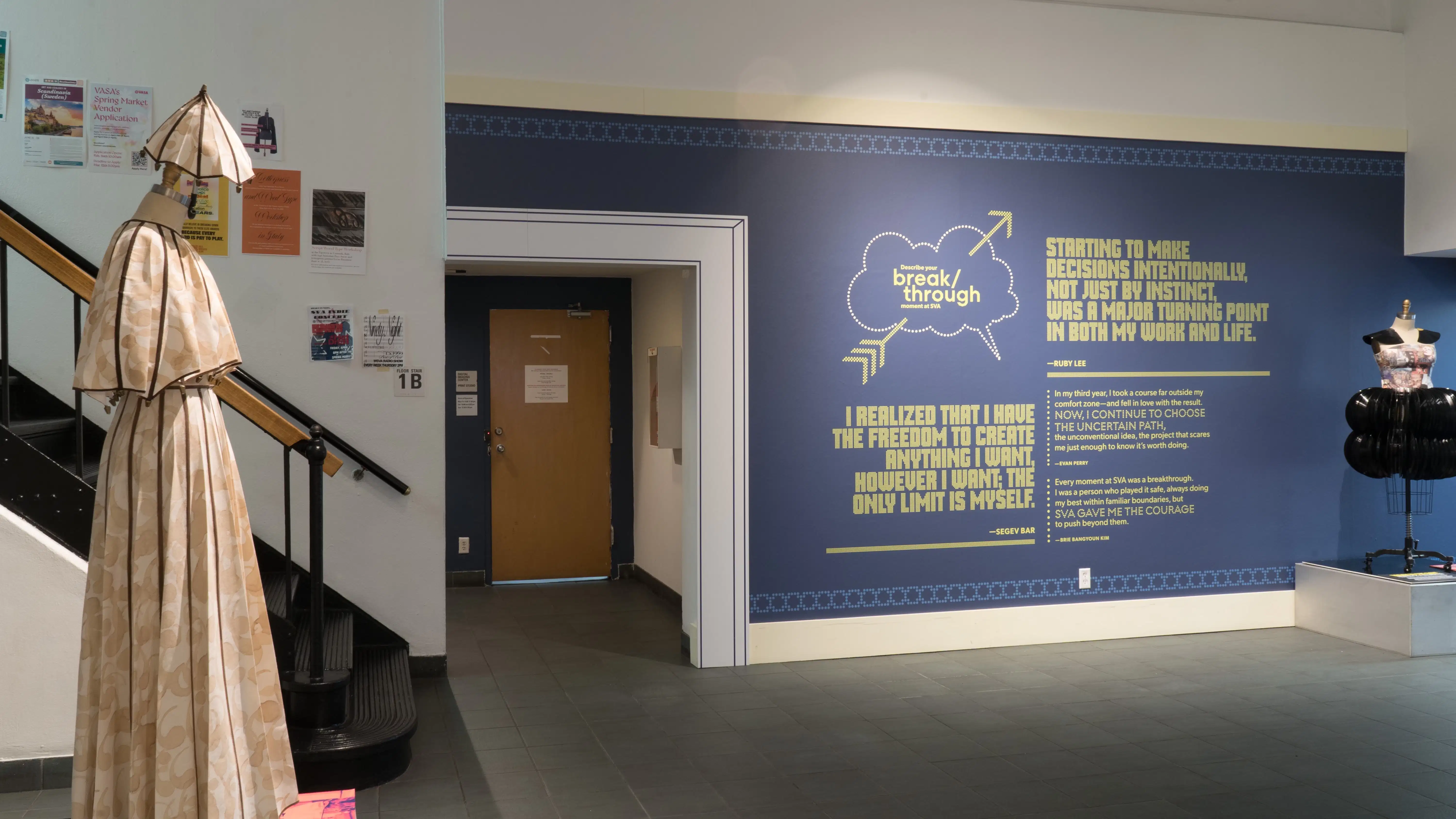 Quotes and information about the exhibition are presented in vinyl text on a wall leading into the gallery lobby. Beside them, a mannequin dressed in a costume made of vinyl records stands on a pedestal.