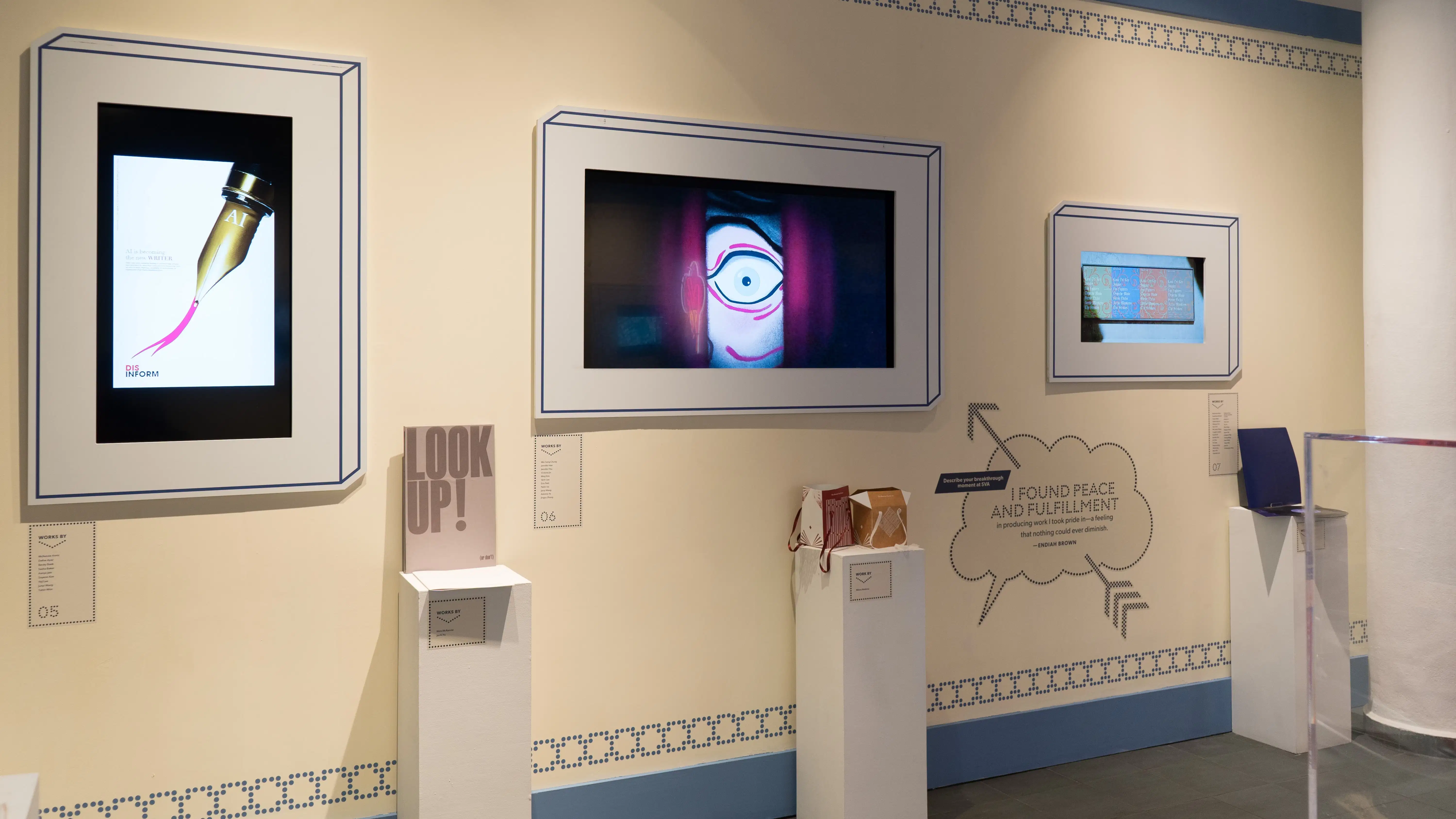Three framed monitors of various sizes hang on a wall. They each play different advertising and design projects. Each monitor has a small pedestal holding books or objects in front of it.