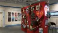 A red wall in the center of the room displays many guitars with various designs for their bodies, like snakes and stained glass windows. On the surrounding walls, design and advertising projects play on monitors.