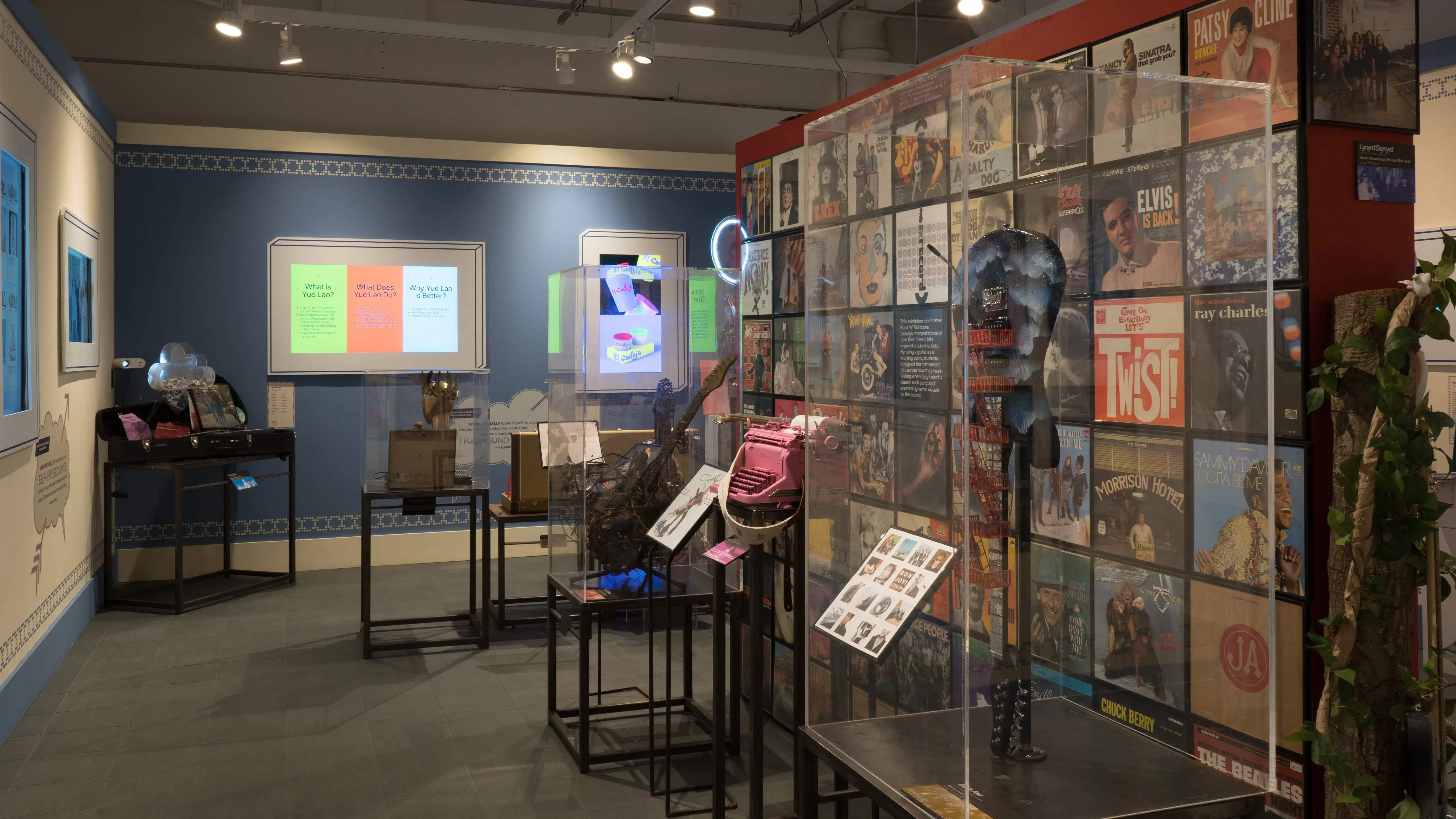 On the opposite side of the red wall, more guitars are presented on pedestals covered by plexiglass bonnets. On the surrounding walls, design and advertising projects play on monitors.