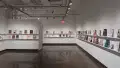 In the last room of the gallery, four walls are displayed. On all these walls, several books are displayed on two long floating shelves, and some books are accompanied with business cards.