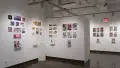 In the first half of the last room of the gallery, there are three walls shown. On the left wall, there are several horizontal and vertical prints displayed, all accompanied with a personalized book and zine. In the corner of the space, a pedestal displays a box with an herbal tea kit. The center wall after the corner displays several vertical and horizontal prints, both groups of prints accompanied with personalized books. The furthest wall behind the first two walls mentioned display horizontal prints, each accompanied with personalized books.