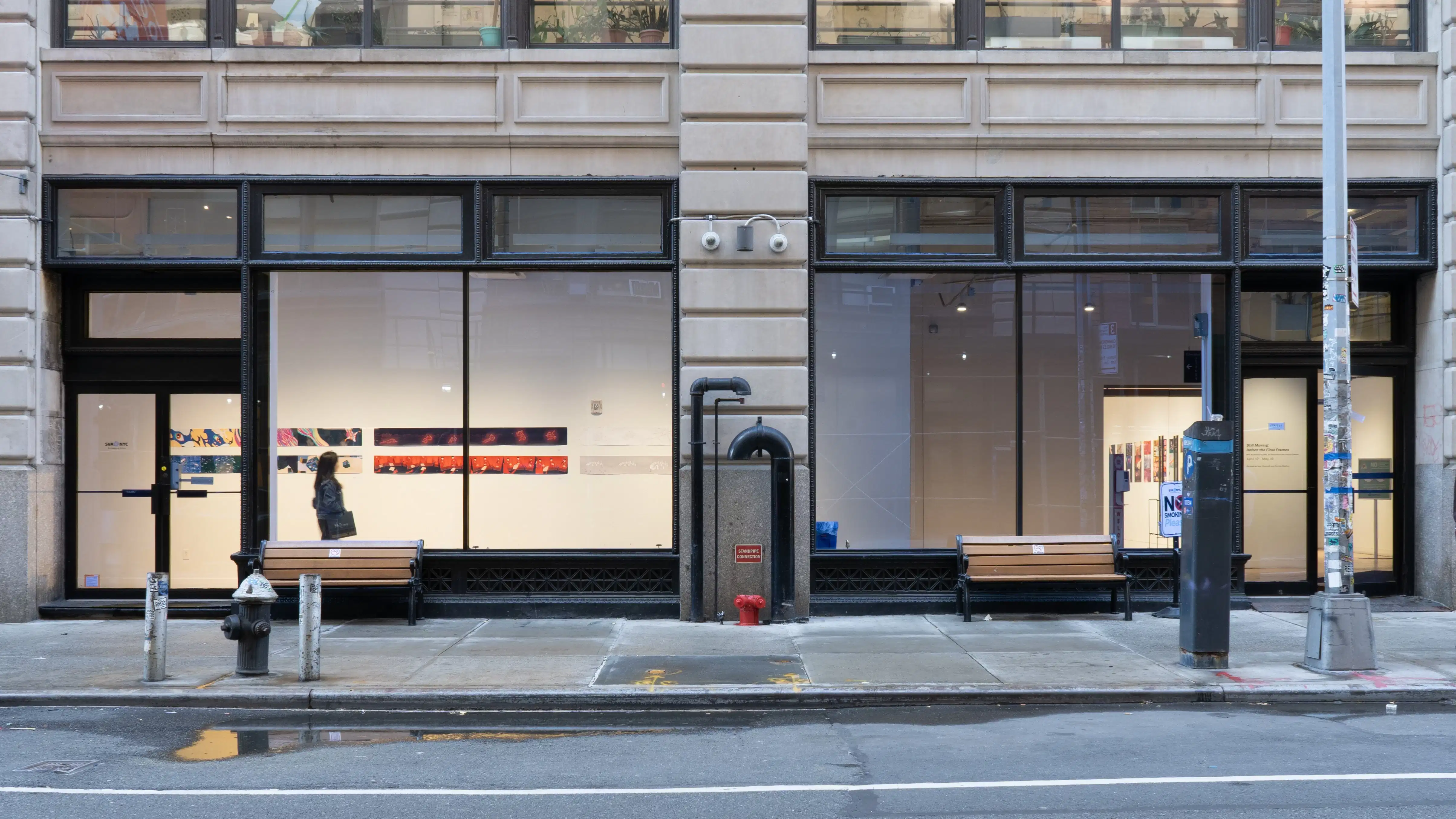 A view from outside the SVA Flatiron Gallery Windows shows a visitor looking at the prints. 