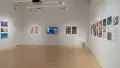 An overview shot of the SVA Flatiron Gallery, showing many colorful prints by BFA Animation students pinned to the walls. A monitor plays clips on the back wall.