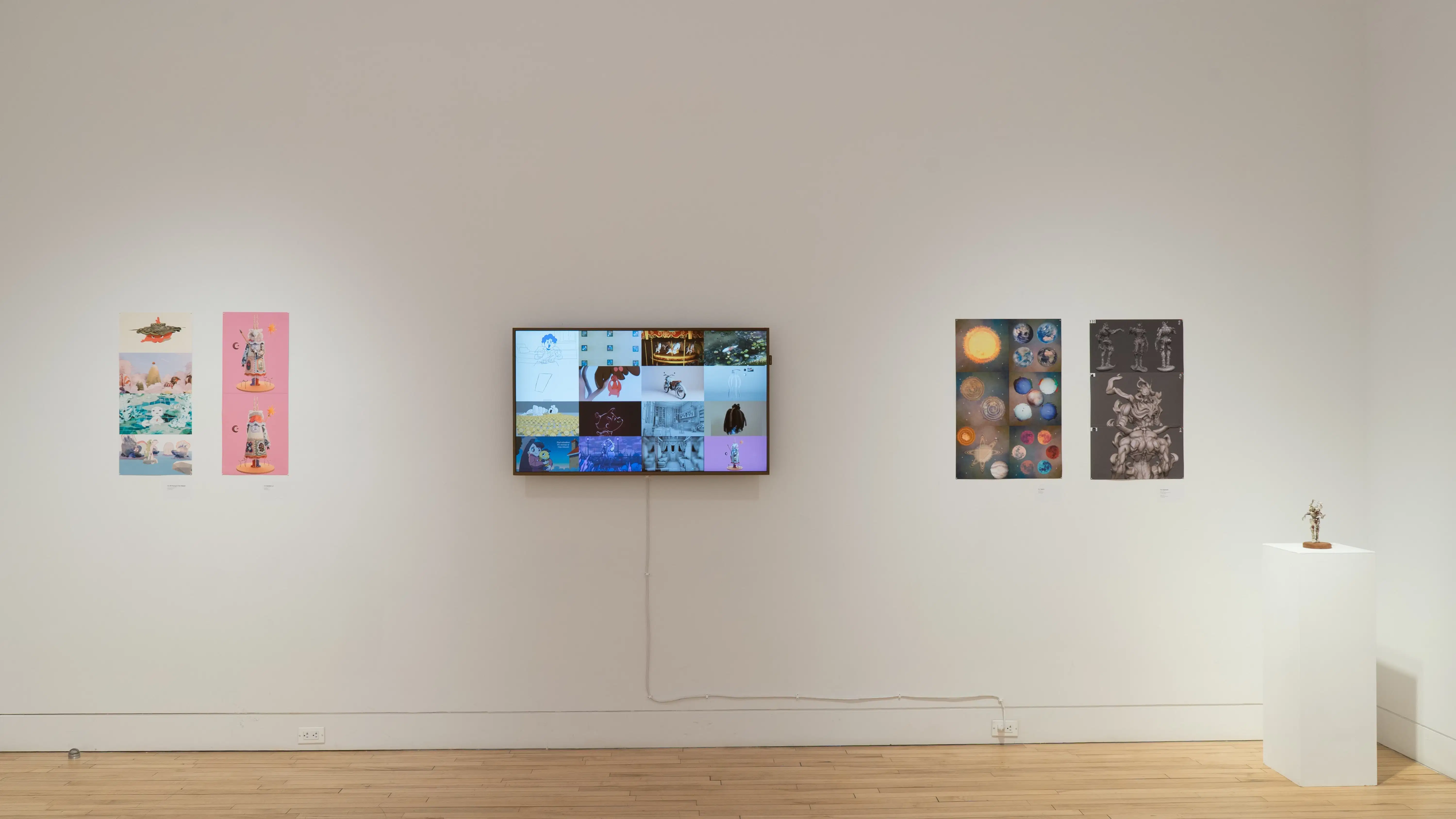 A straight shot of the SVA Flatiron Gallery's north wall, showing four colorful prints by BFA Animation students pinned up on each side of a monitor; a sculpture sits atop a pedestal in the right corner.