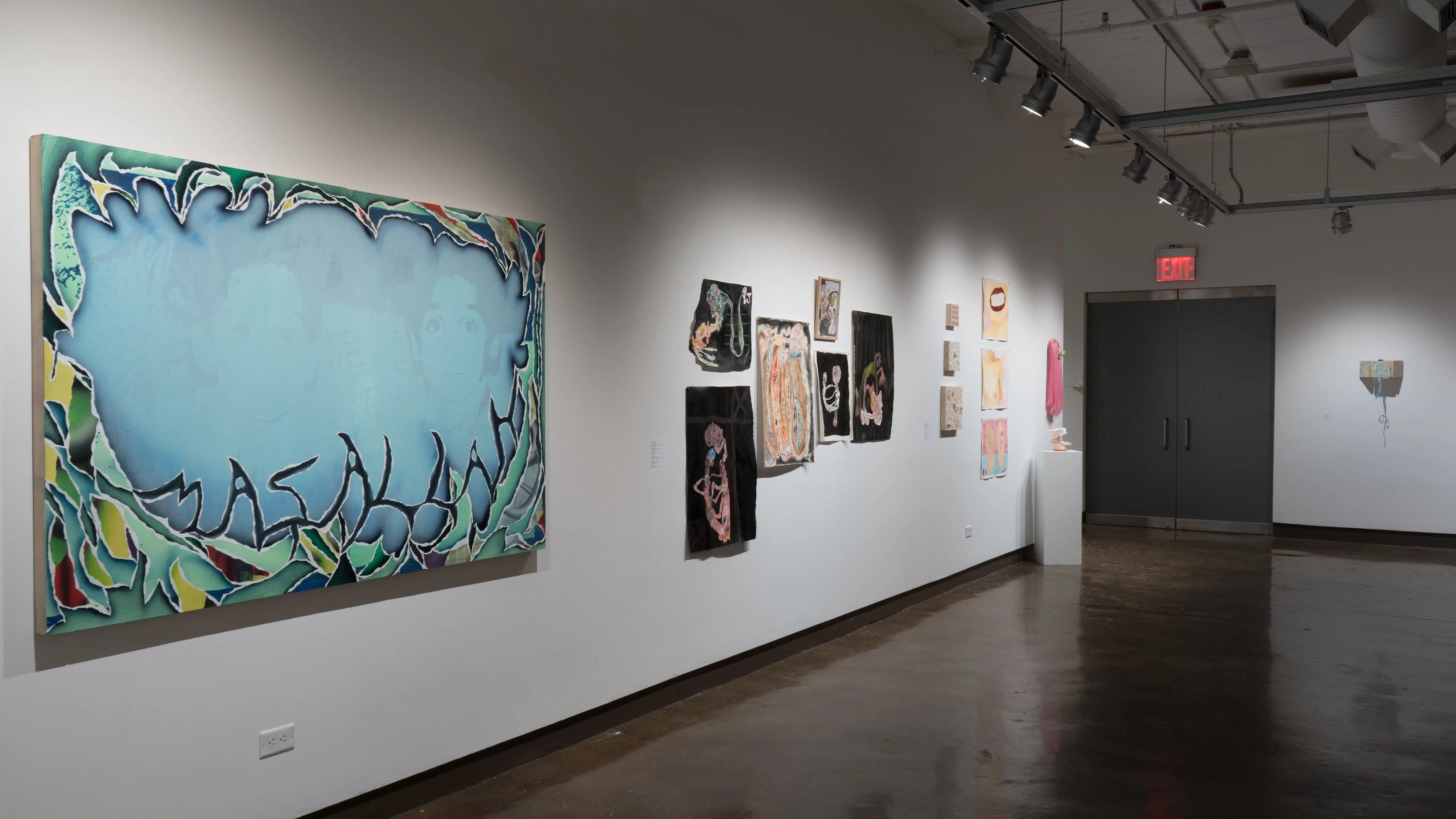 In gallery three, a large horizontal canvas depicts a faded image of two children’s faces, while colorful, textured shapes surround them and spell out “Masallah.” Further along the wall, works on paper using blacks and skin tones hang next to pink and fleshy watercolors and sculptures.