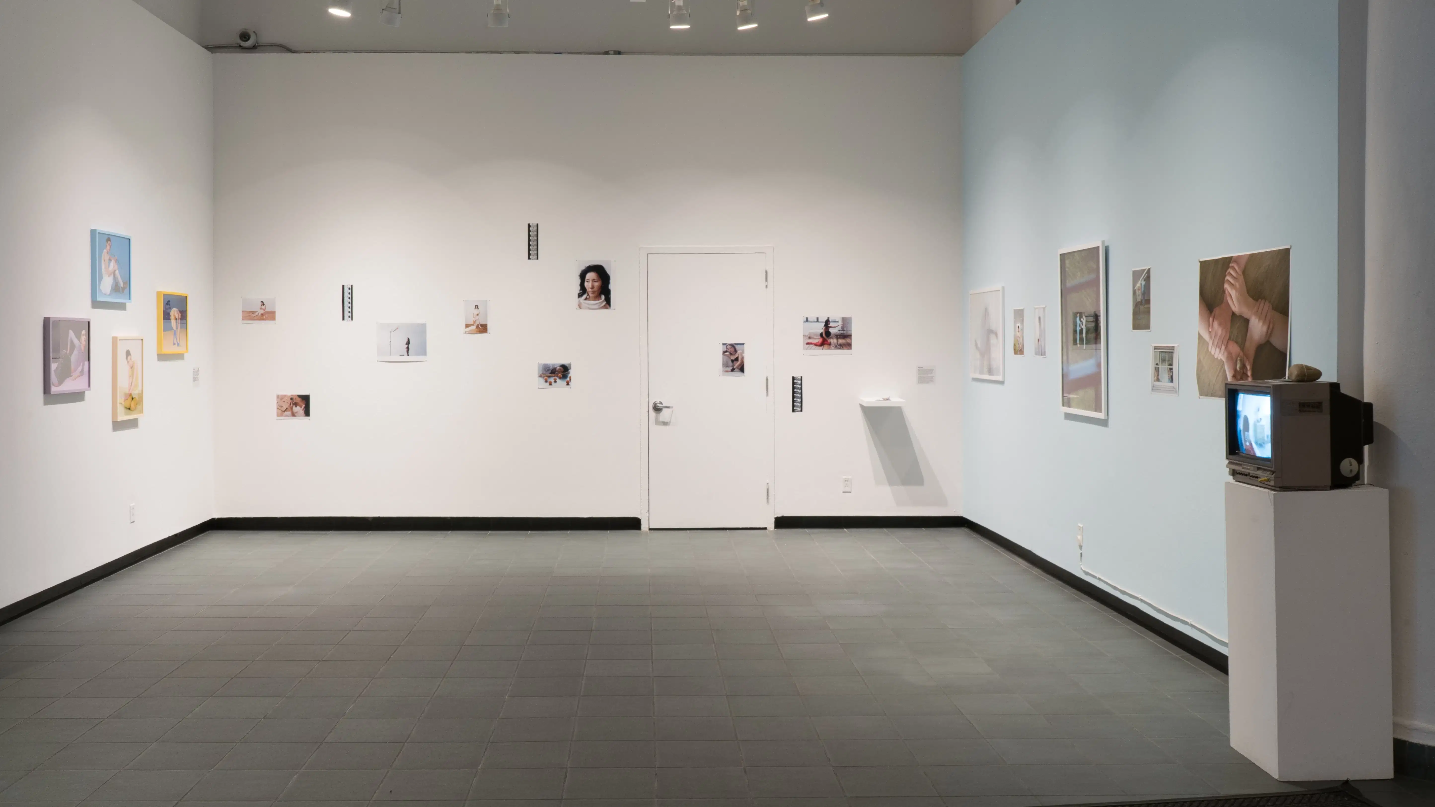 A wider view of the Gramercy Gallery lobby. Photographs hang on every wall and a box television sits on a pedestal to the far right of the image.