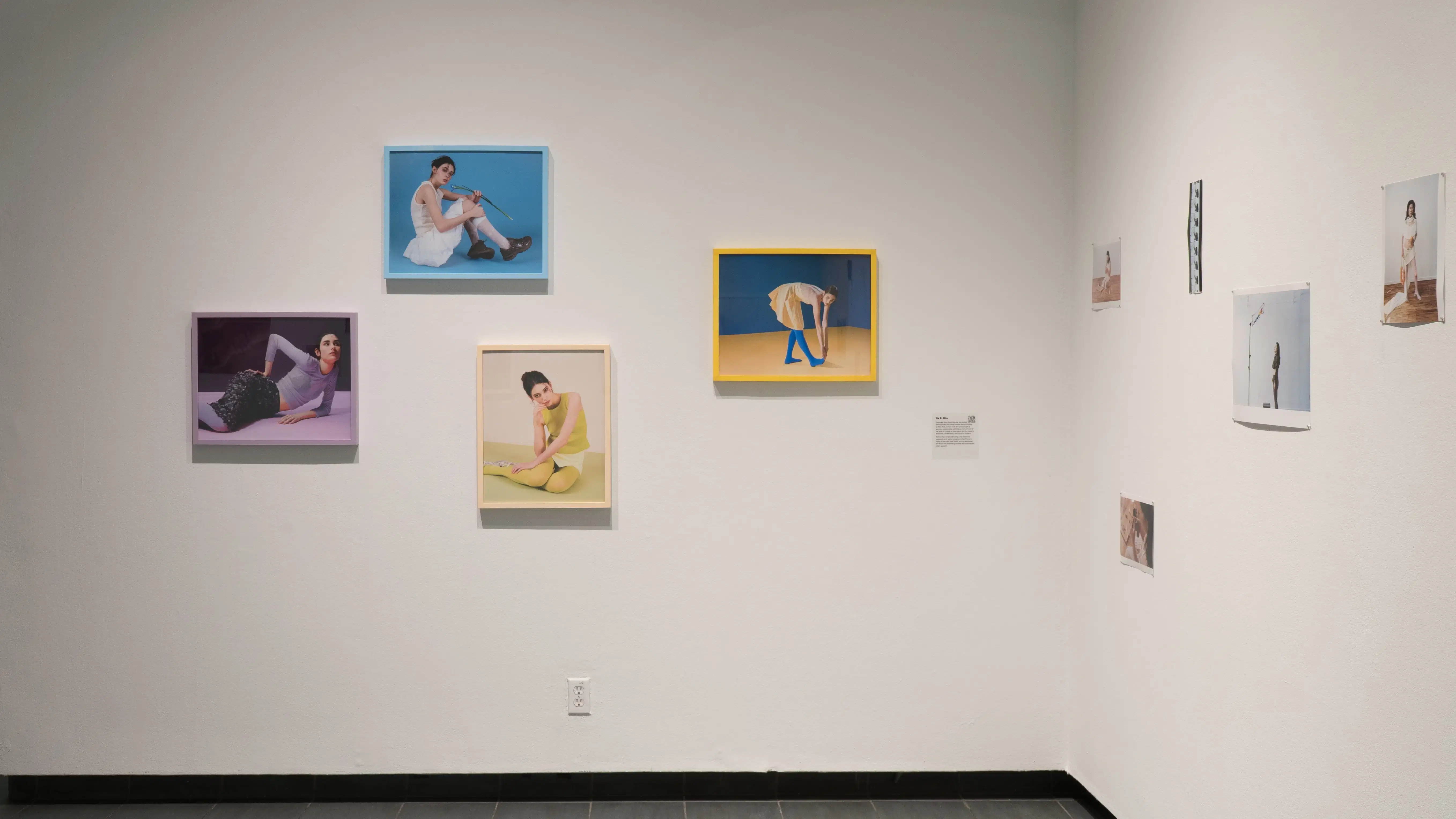 Colourful images whose contents match their frames in the lobby of the SVA Gramercy Gallery. On a wall perpendicular are unframed images by another artist.