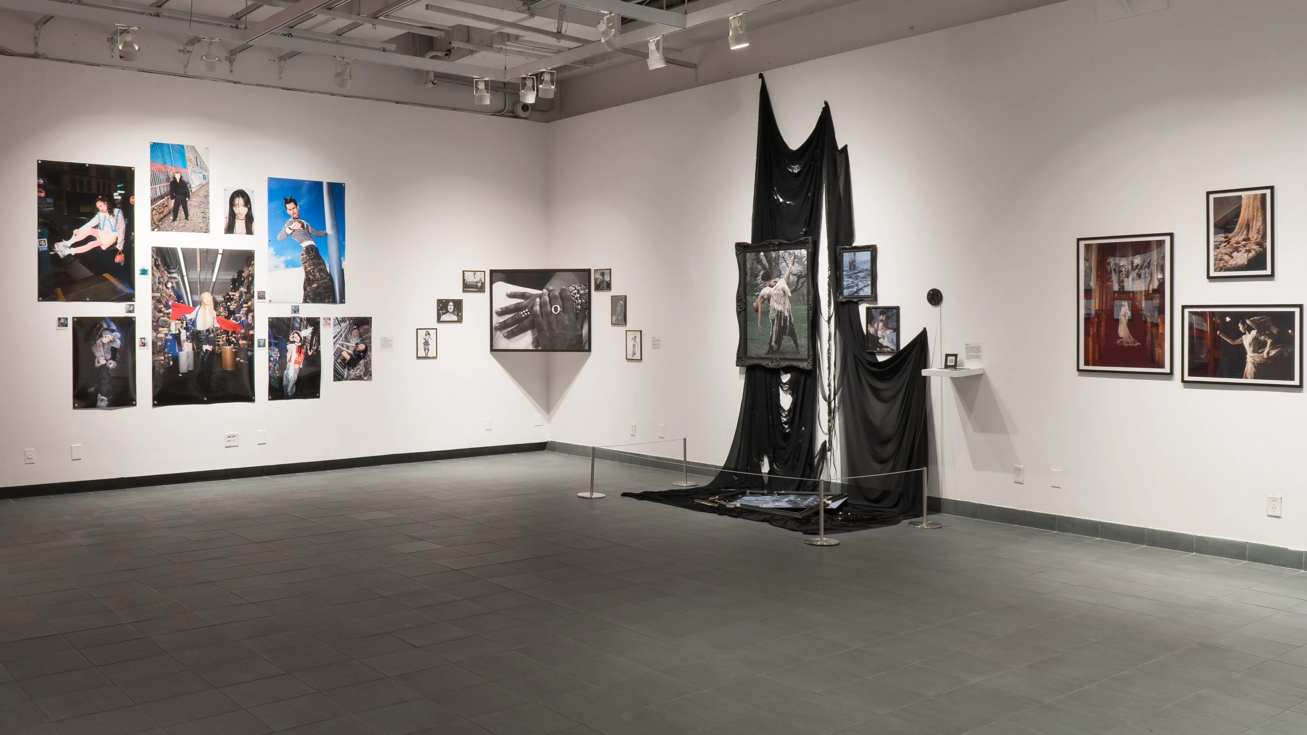 Several works on display in the SVA Gramercy Gallery. One display features images in decorative frames hung in front of cascading black cloth.