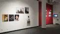 Another angle of the previous image. The wall is painted red partway through and features more photography by another artist. Perpendicular to that wall is a video display.