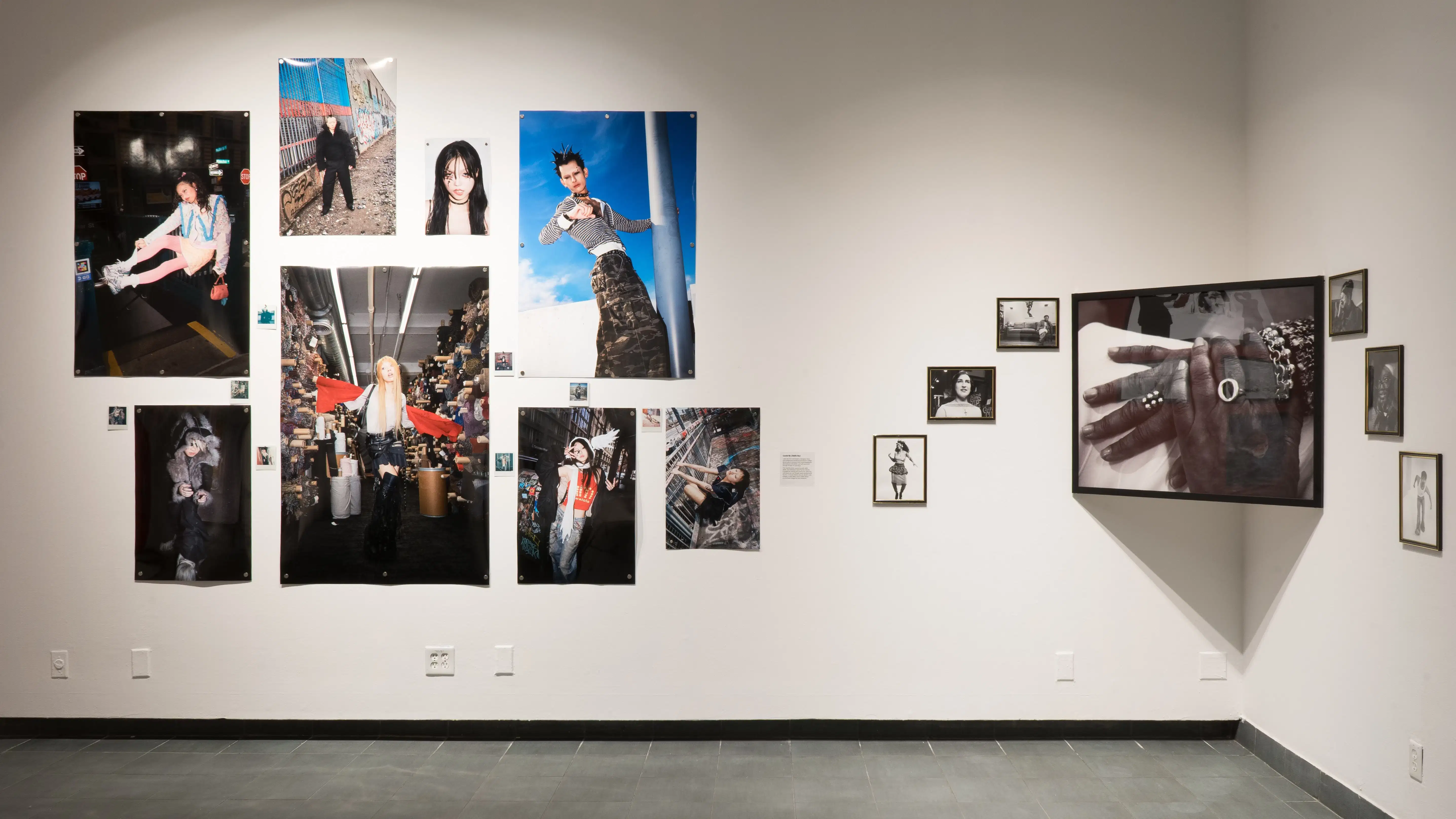 Images of fashionable young people arranged on a wall in the SVA galleries. To the right of those images is a series of black and white pictures arranged around a larger portrait of a person’s hands.