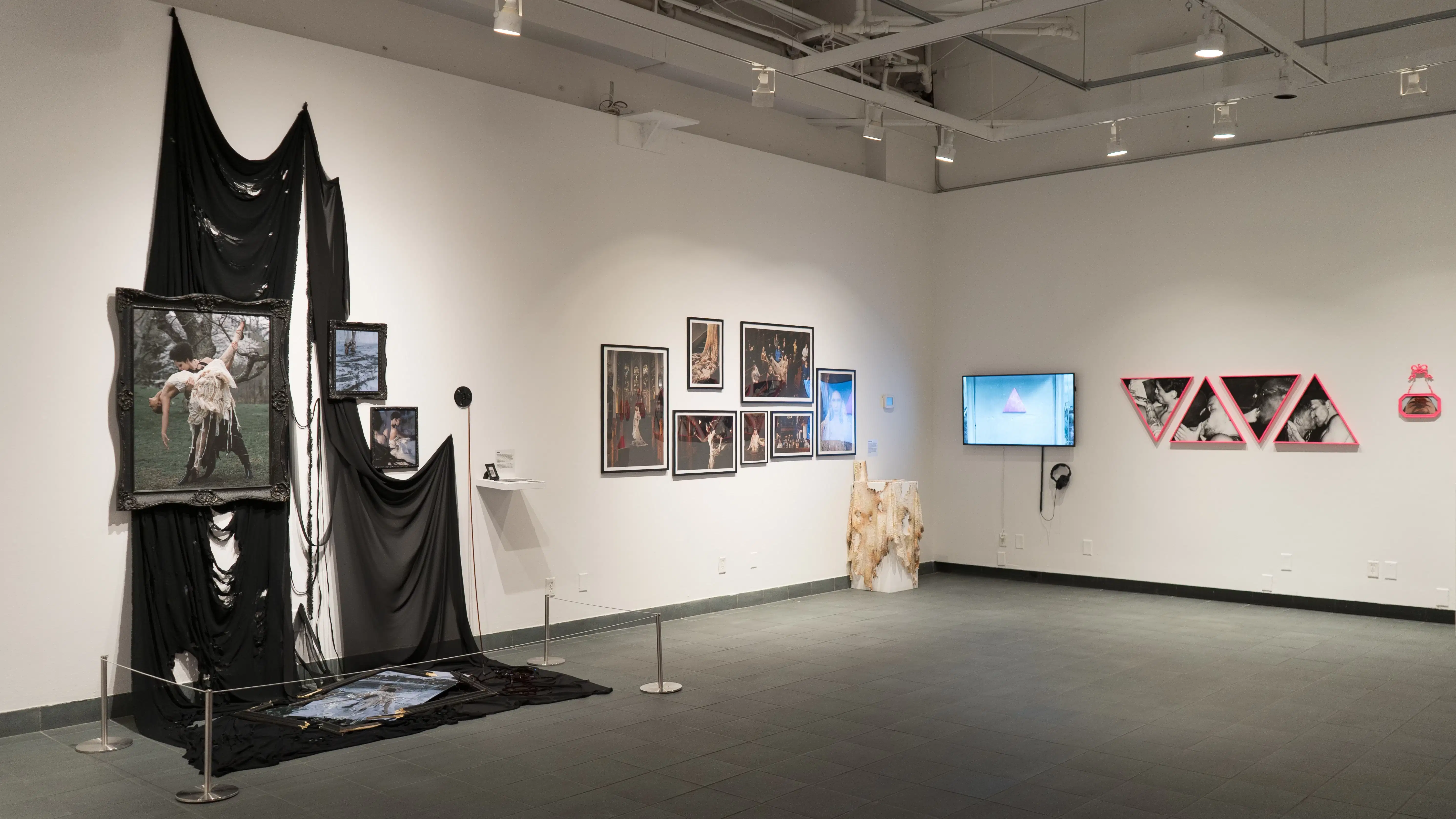 Several works on display in the SVA Gramercy Gallery, including a gothic looking one, images of a model in church, and images of men in triangular pink frames.