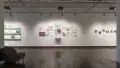 A straight view of the west wall at the SVA Chelsea Gallery. There are three projects visible on the wall: watercolor paintings on shelves on the left, two rows of pinned illustrations in the middle, and small paintings on panel on the right.
