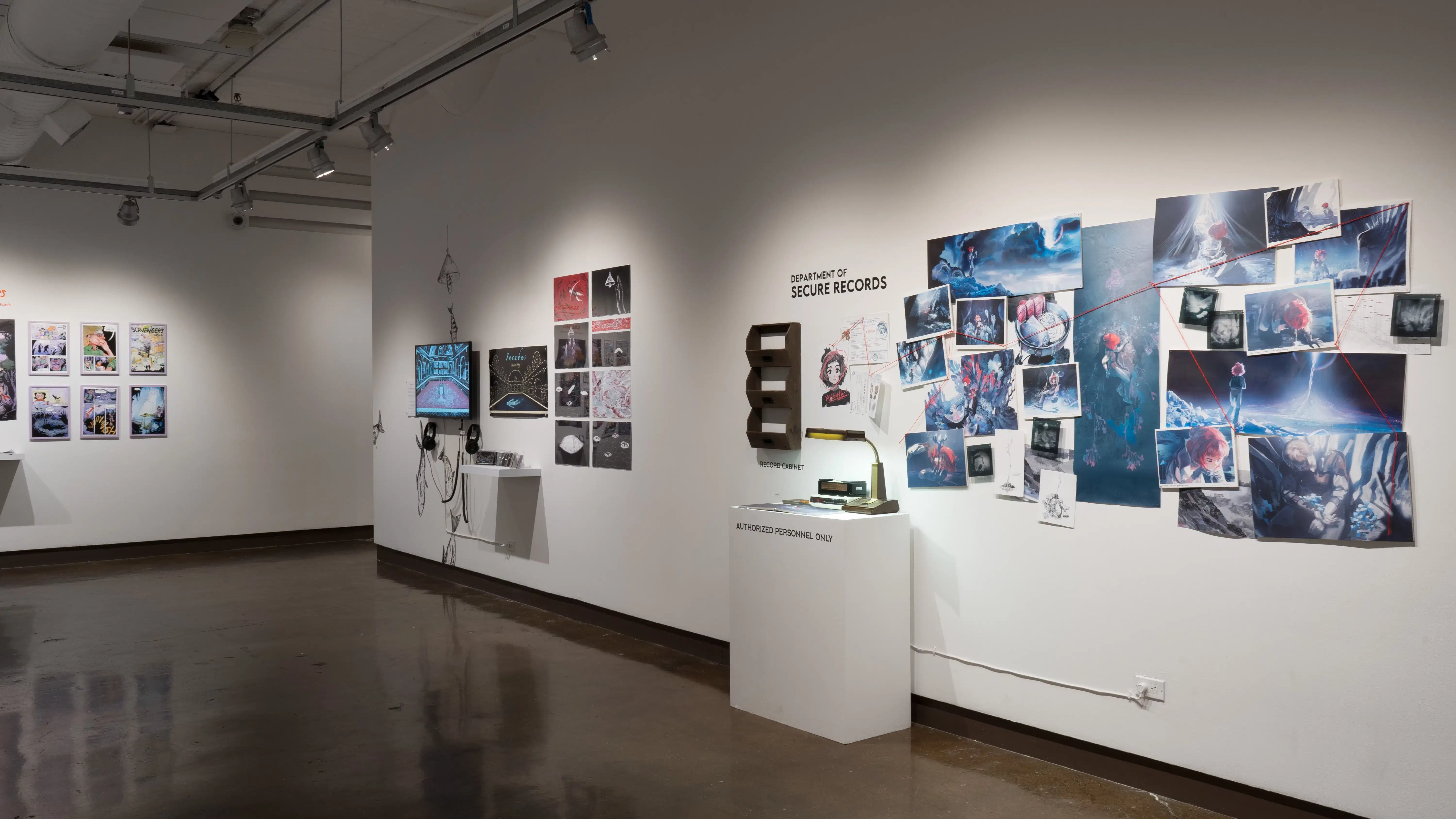 On a wall of gallery two, there are prints hung next to a monitor and headphones. Further to the right, another project’s prints are organized into a constellation, and a red string leads between images like a detective’s investigation board. A small radio and lamp sit on the pedestal beneath them.