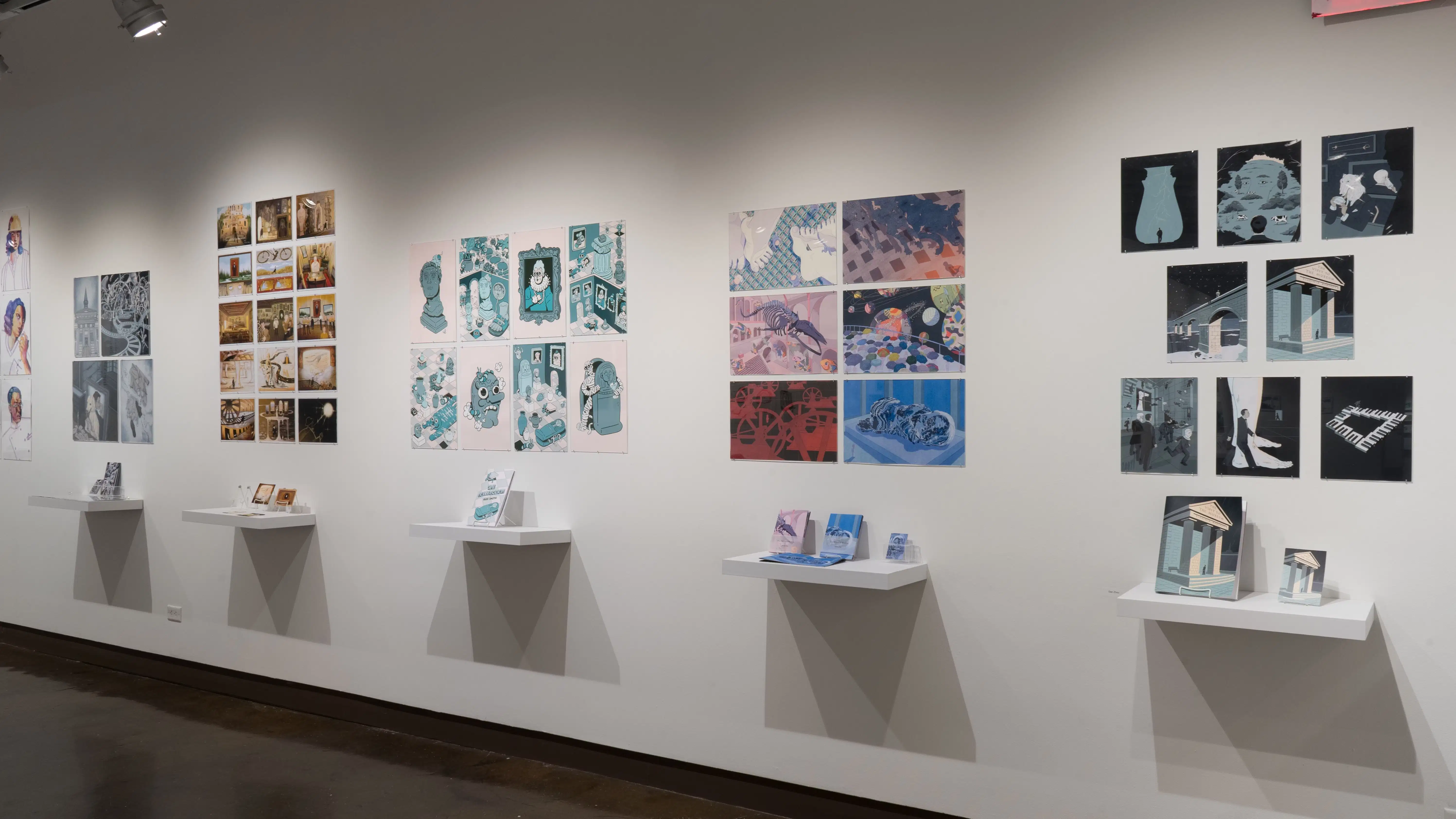 Along the back wall of gallery four, several illustration projects made up of prints or original drawings and books hang beside each other.