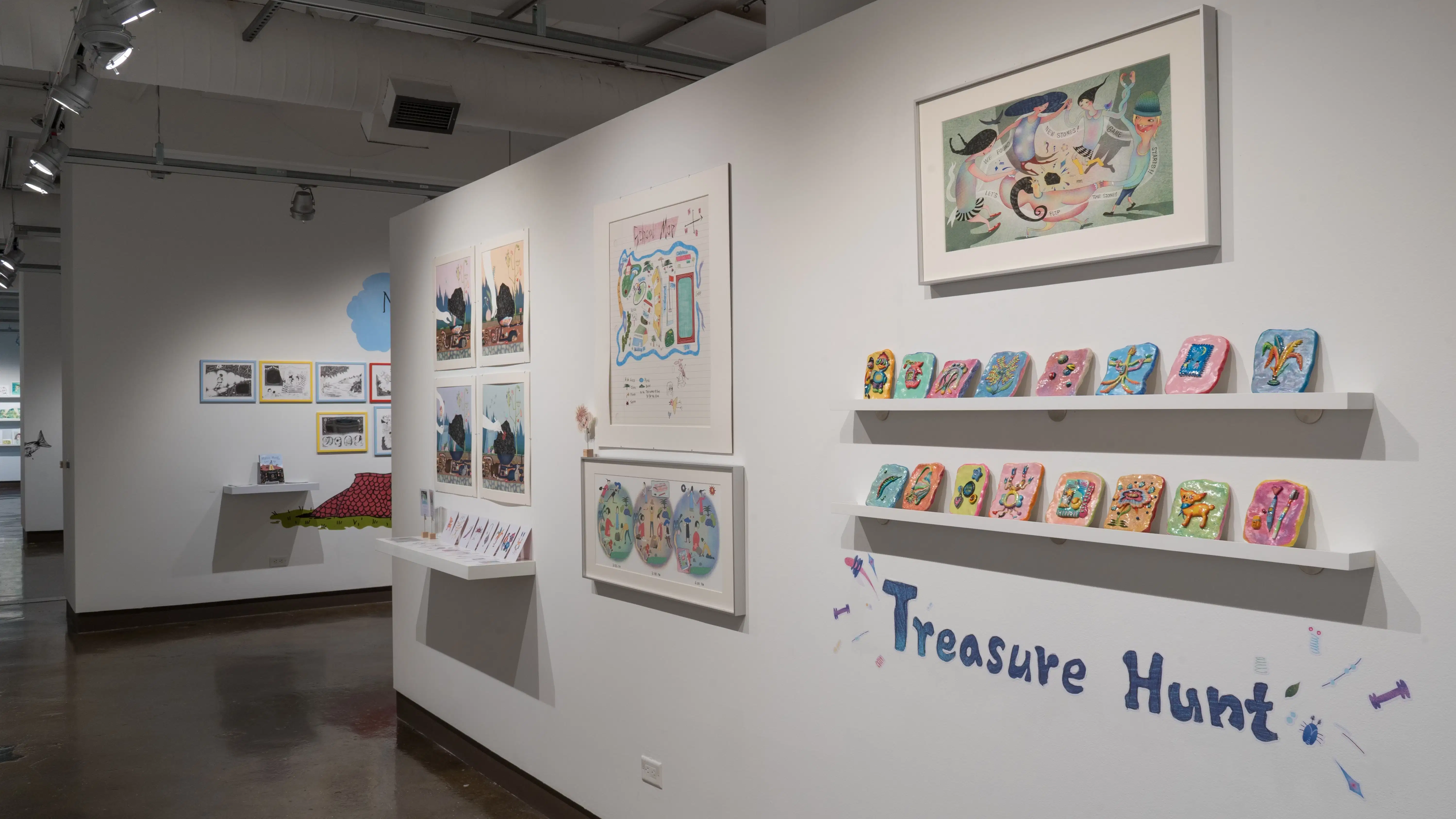In the right hallway leading from gallery three to gallery four, colorful, ceramic sculptures line two shelves under a framed illustration. The title “Treasure Hunt” appears below the installation.