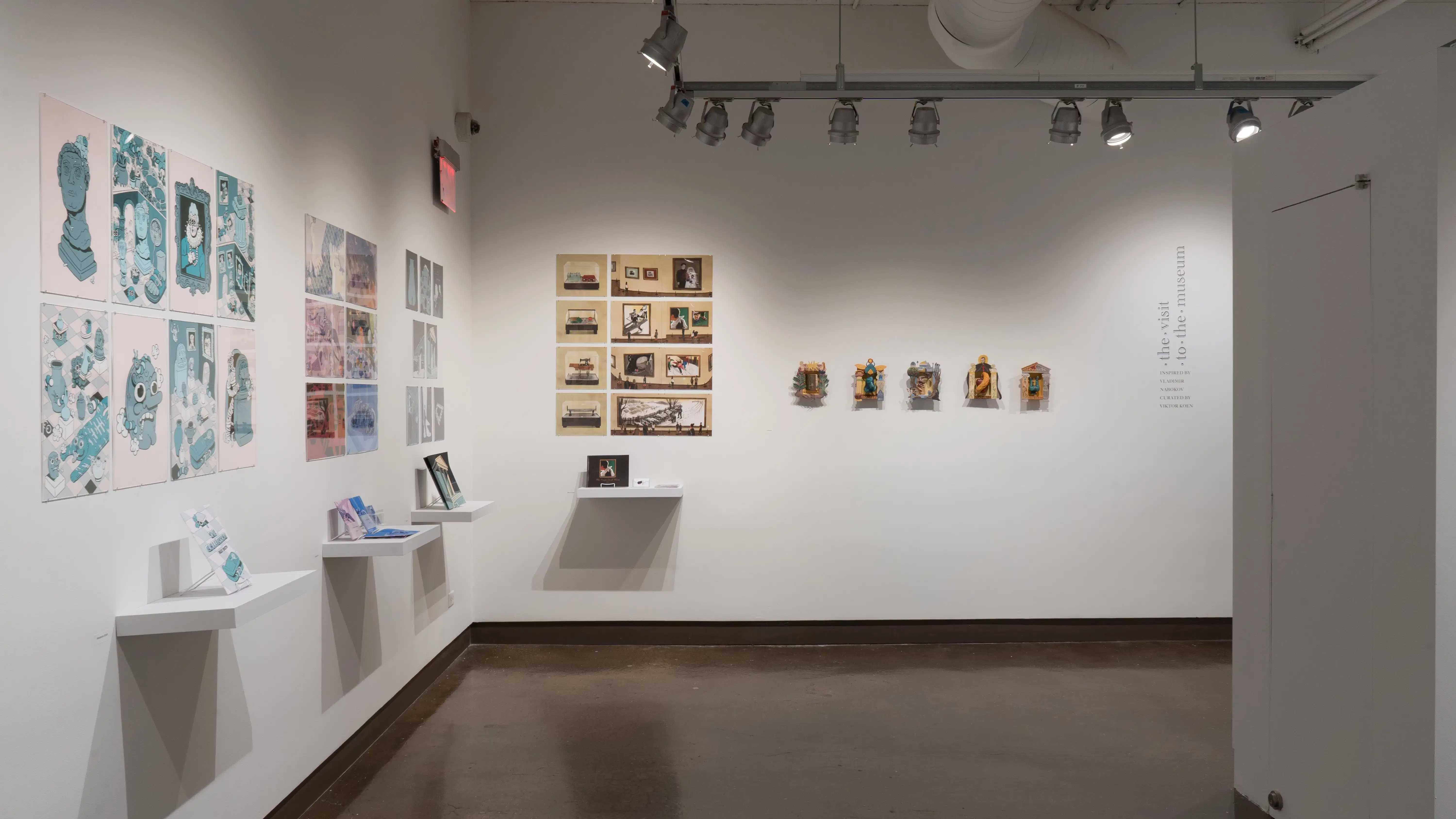 In the right corner of the space, five projects are displayed on the wall side by side. Some projects are presented with pinned prints and books, while others use small sculptures.