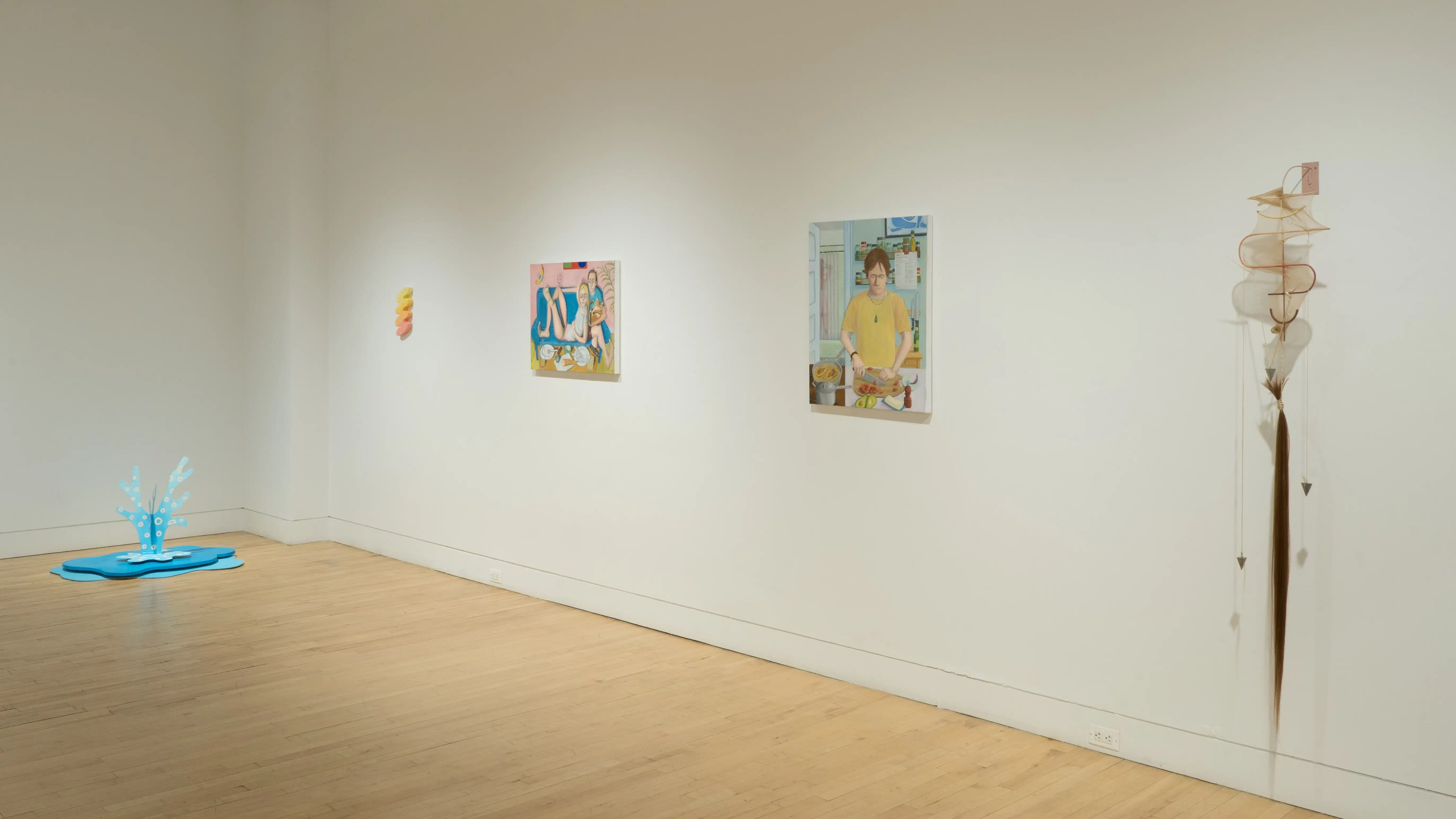 The blue fountain sculpture is visible in the corner to the left of the wall where the squiggle painting, the figurative paintings, and the abstract sculpture hang.