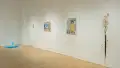 The blue fountain sculpture is visible in the corner to the left of the wall where the squiggle painting, the figurative paintings, and the abstract sculpture hang.
