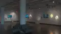 Several monitors on the walls play animated videos in gallery one of the SVA Chelsea Gallery. Each monitor is accompanied by prints and objects, such as small sculptures or dioramas. 